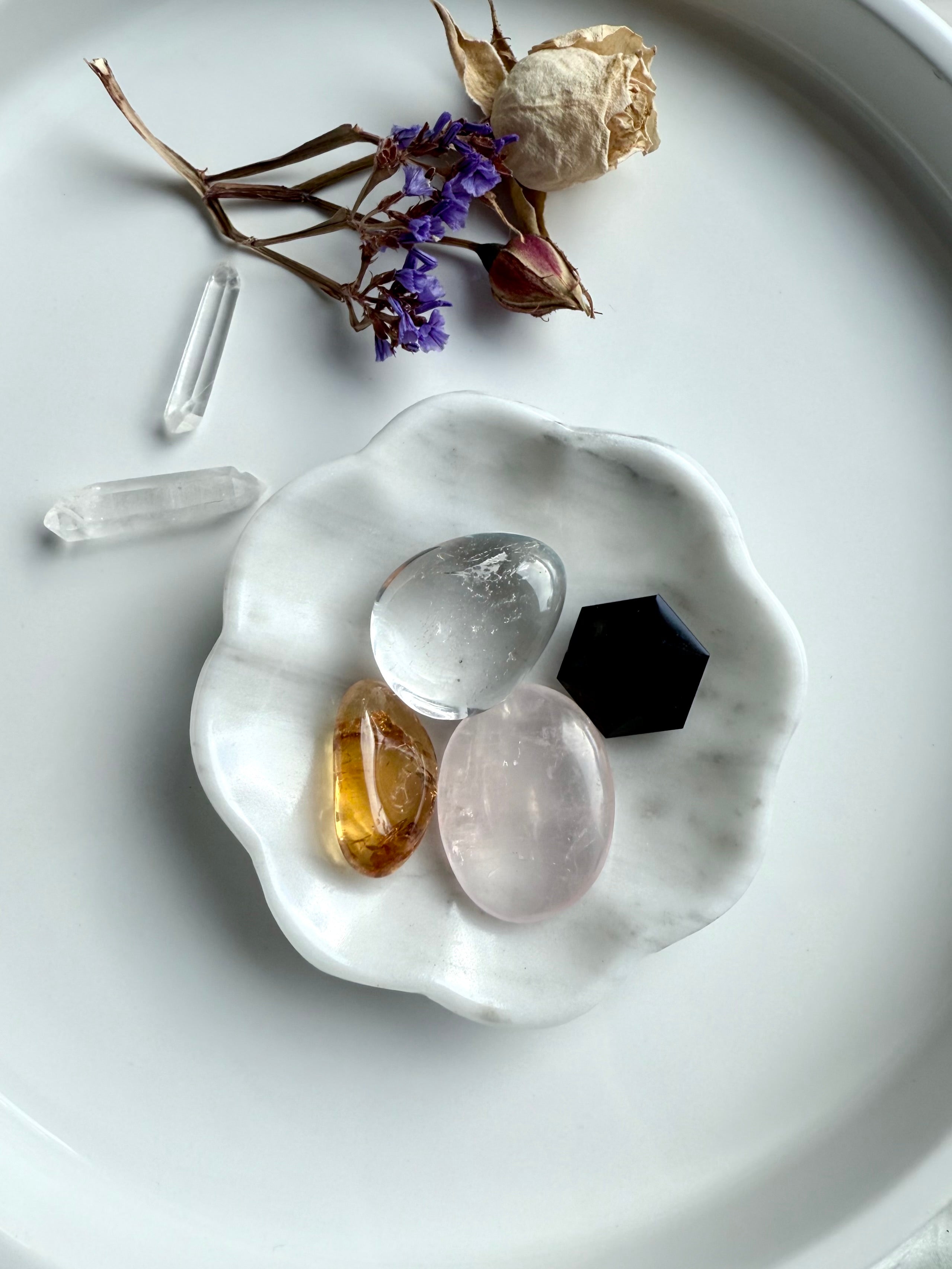 White marble daisy bowl styled with a mini crystal collection of rose quartz, clear quartz, citrine tumbles, with a black obsidian hexagon