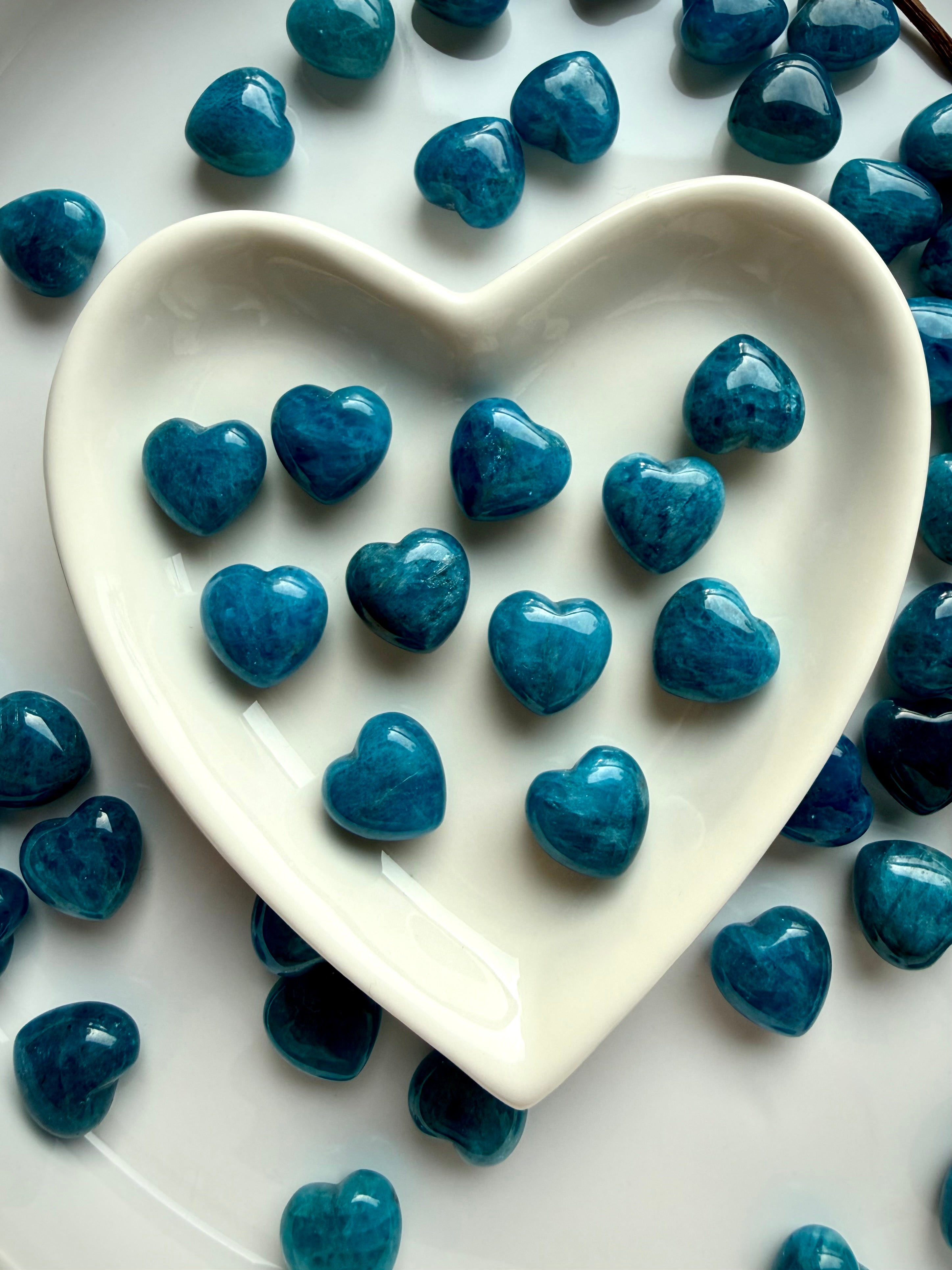 Mini Blue Apatite hearts resting in a white ceramic heart bowl, ideal for crystal grids, altar décor, and sacred gifting
