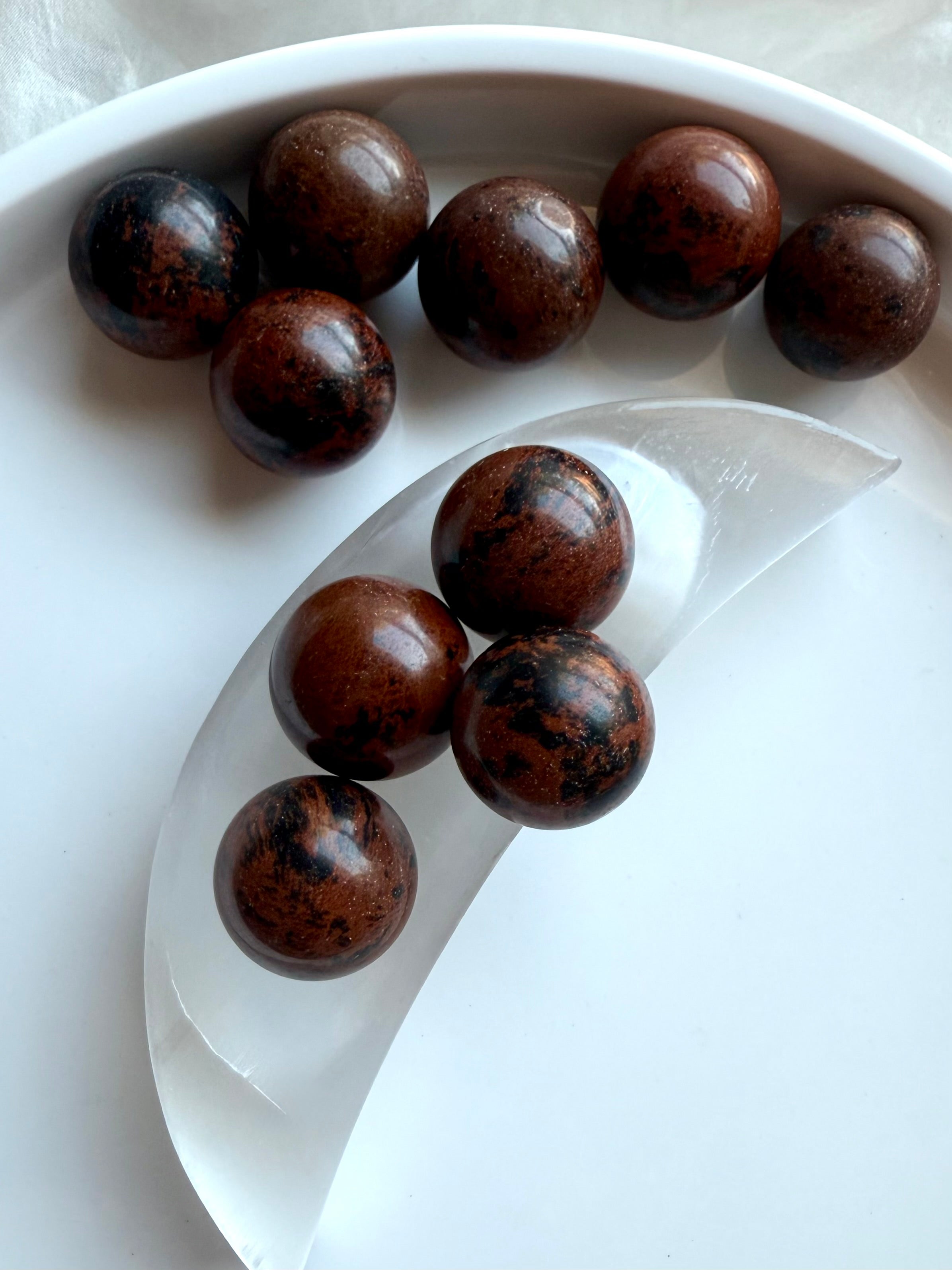 Mahogany Obsidian mini crystal spheres on selenite moon bowl – grounding and protective Root Chakra stones
