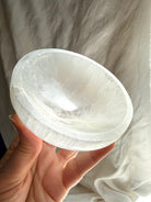 one of a kind selenite charging bowl held in hand, translucent white crystal bowl with natural inclusions for cleansing and altar use