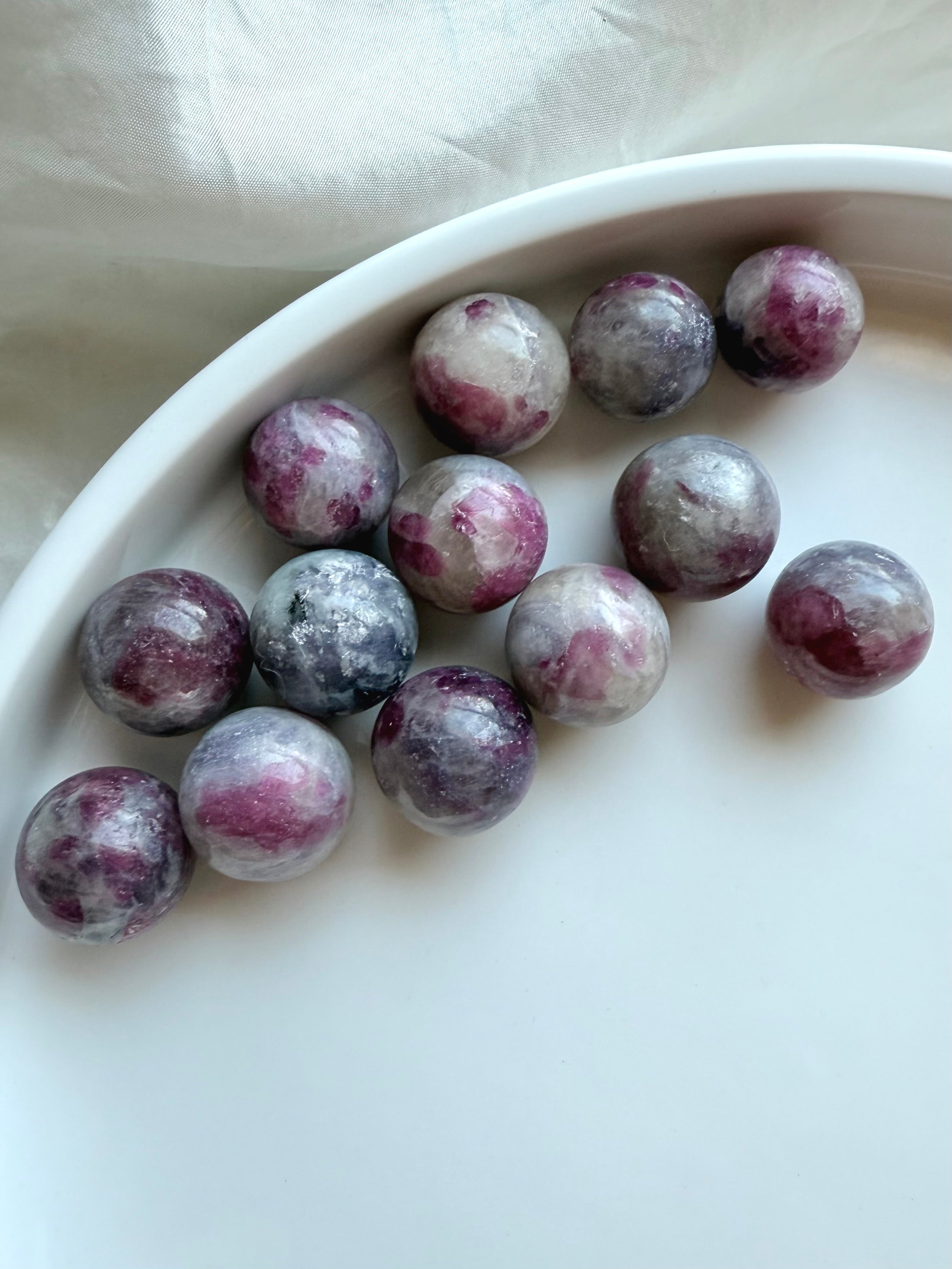 Array of Mini Unicorn Stone spheres with pink tourmaline, lepidolite, and smoky quartz patterns on white dish