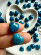 Mini Blue Apatite crystal heart held between fingers, showing glossy polish, rich blue color, and natural stone variation for size reference