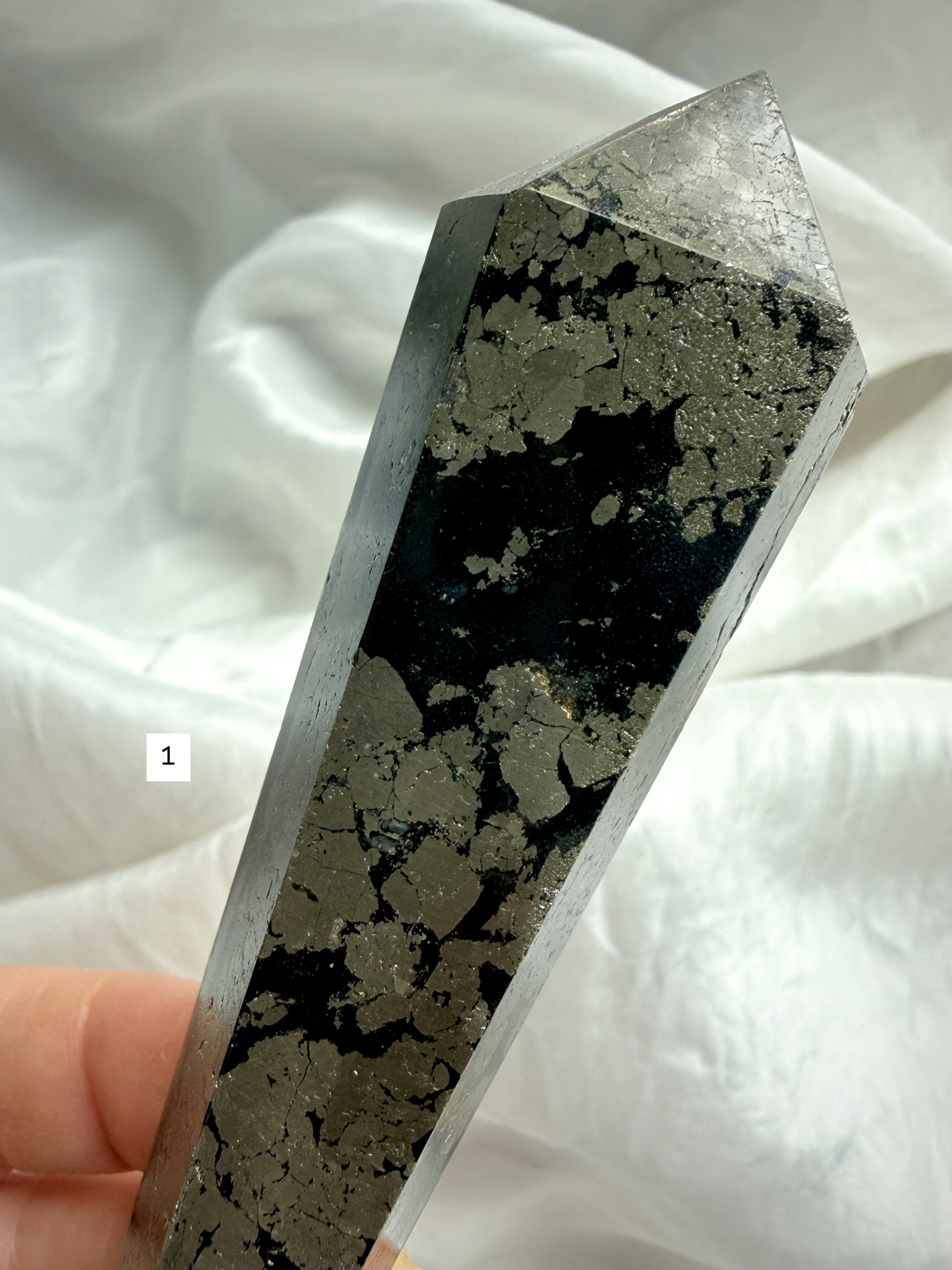 pyrite in black matrix crystal point close up showing metallic gold pattern