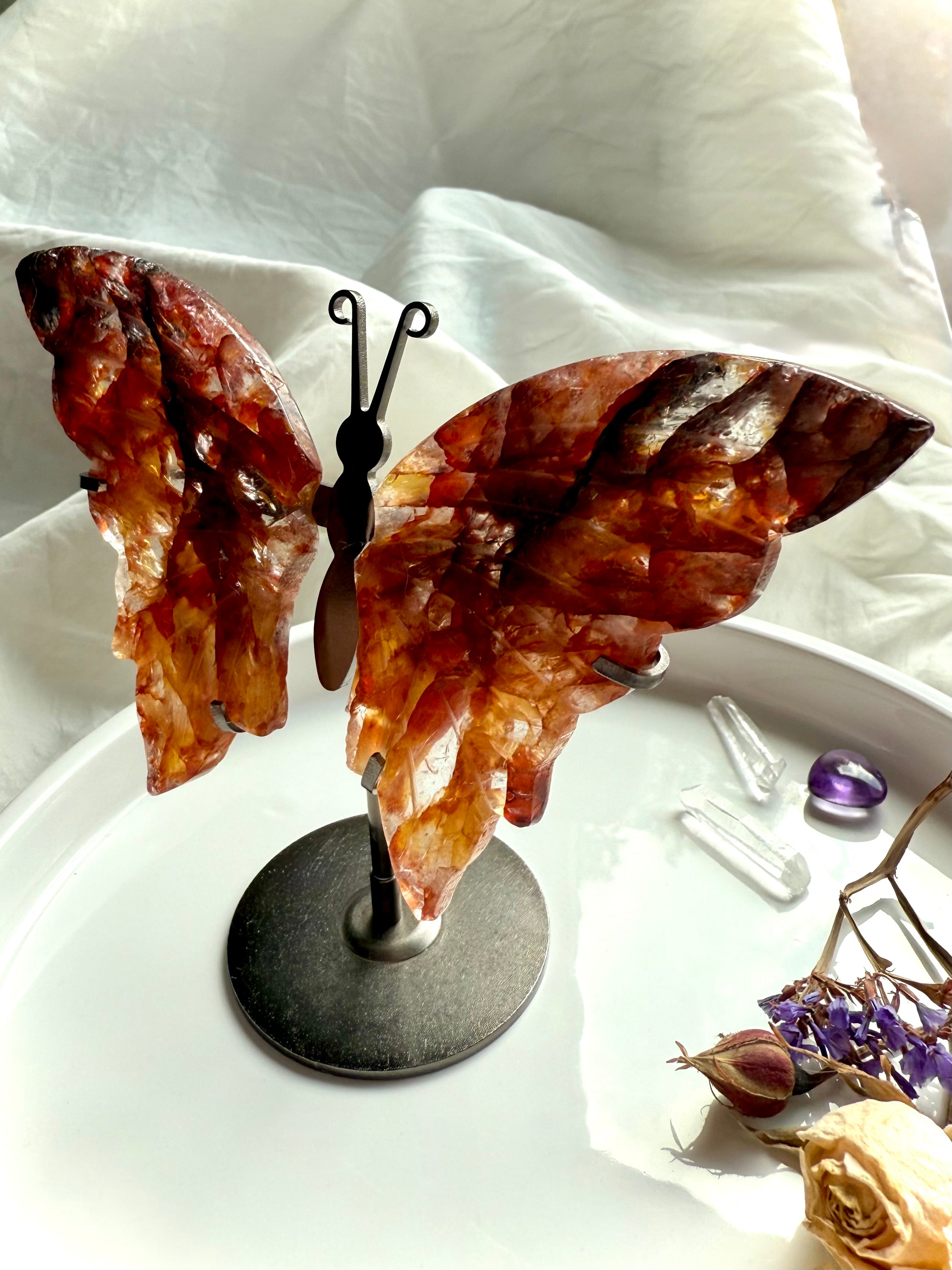 Side view of carved Fire Quartz butterfly wings on bronze-colored stand, highlighting translucent red and gold quartz.