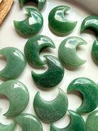 Close up of polished Green Aventurine Crescent Moon crystal carvings showing natural green color, subtle shimmer, and unique patterns