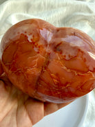 Close up of polished Carnelian geode heart with intricate natural patterns and druzy details