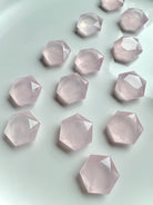 Several faceted rose quartz hexagons on white, mini-sized Heart Chakra crystals with natural veining & soft pink color
