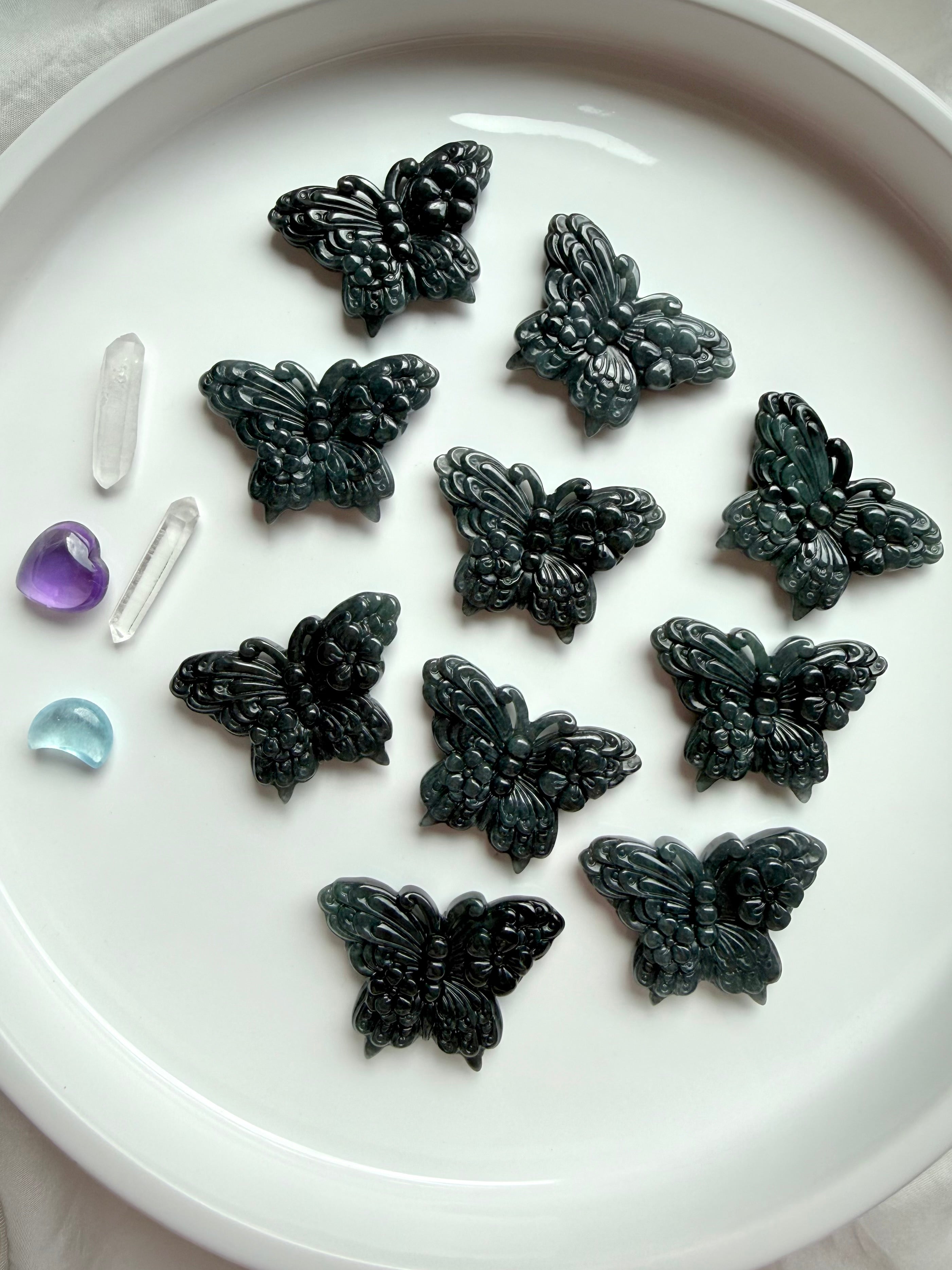 Overhead view of a tray of Wuji jade butterfly crystal carvings made from natural Guatemalan jade gemstone