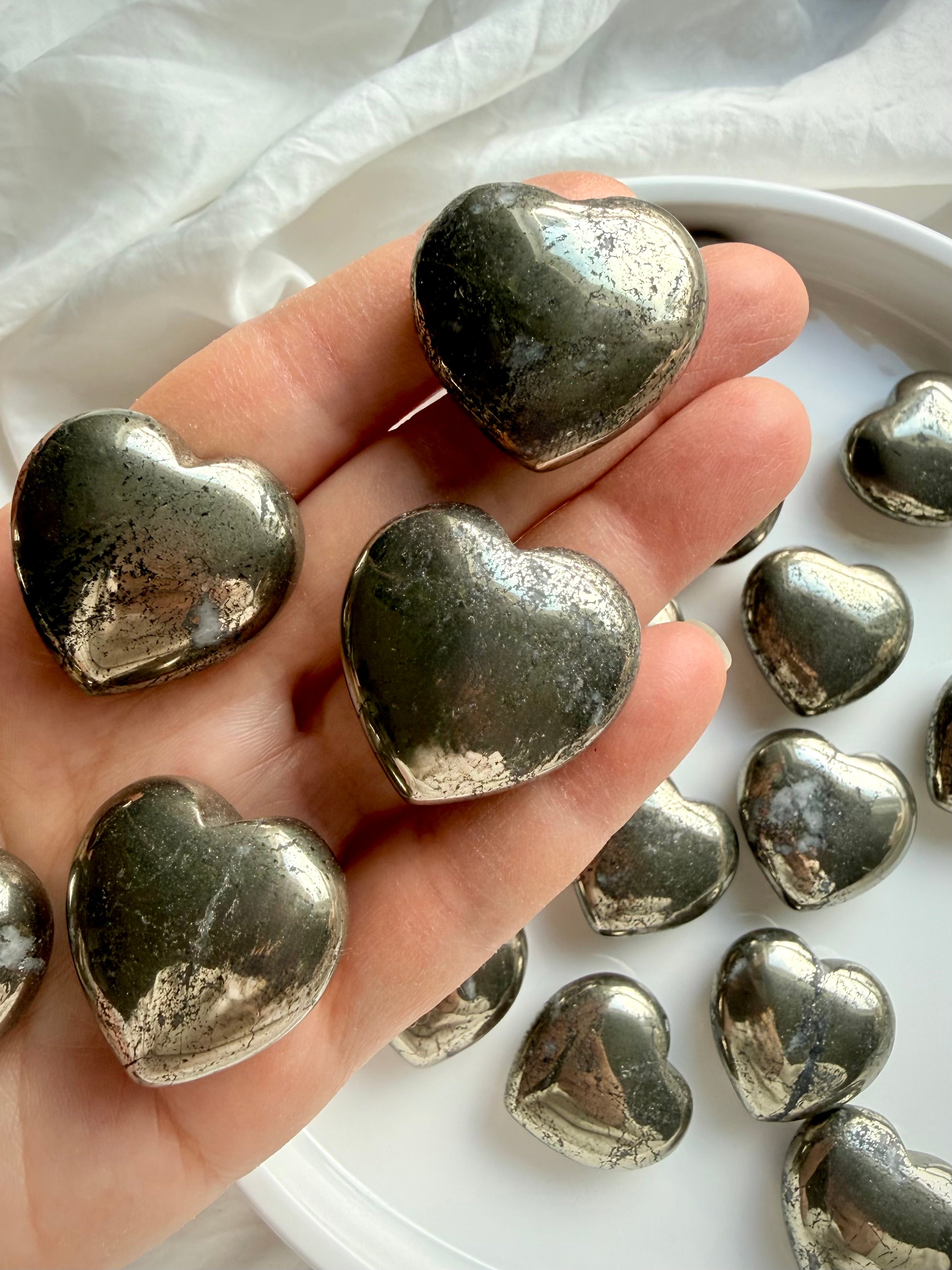 Pyrite heart held in hand, reflective gold crystal for confidence building and abundance rituals