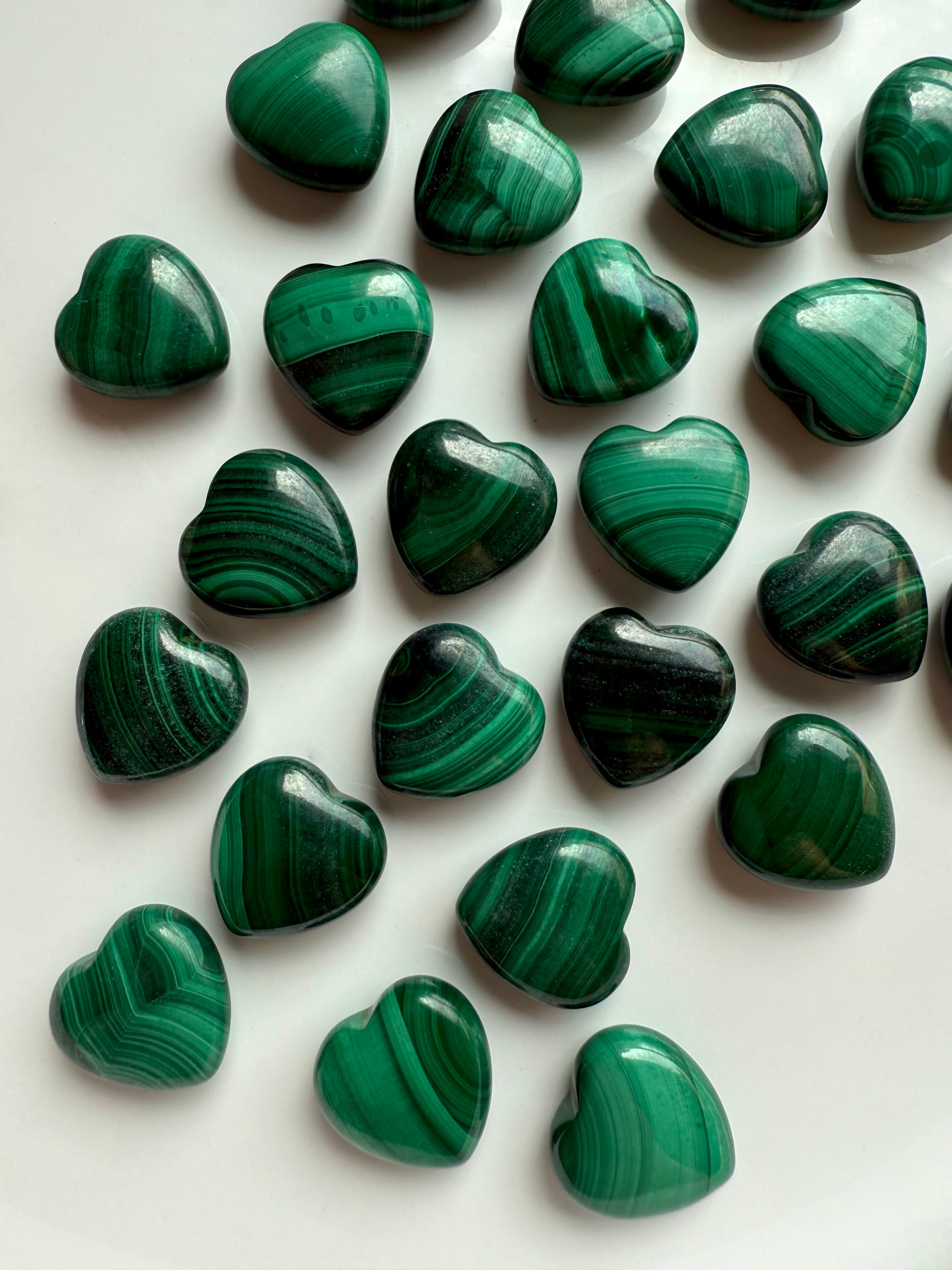 Detailed top-down shot of high-quality Malachite hearts with natural swirling patterns in deep and light green.