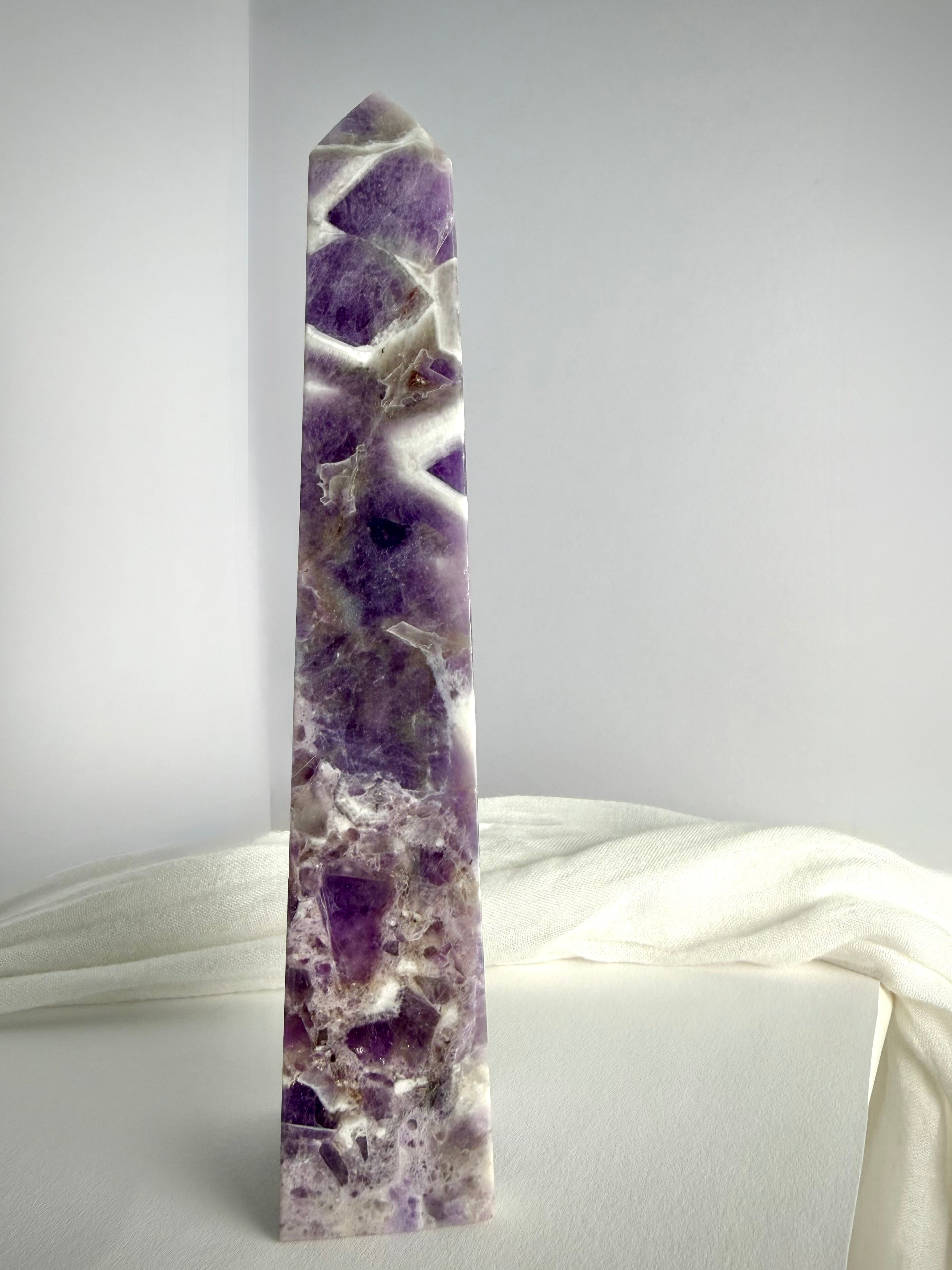 Polished Chevron Amethyst tower standing upright, featuring dramatic purple crystal formations and contrasting white quartz inclusions