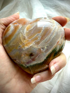 Ocean Jasper heart crystal with natural sea jasper banding, earthy green and warm brown layers, polished meditation stone shown handheld