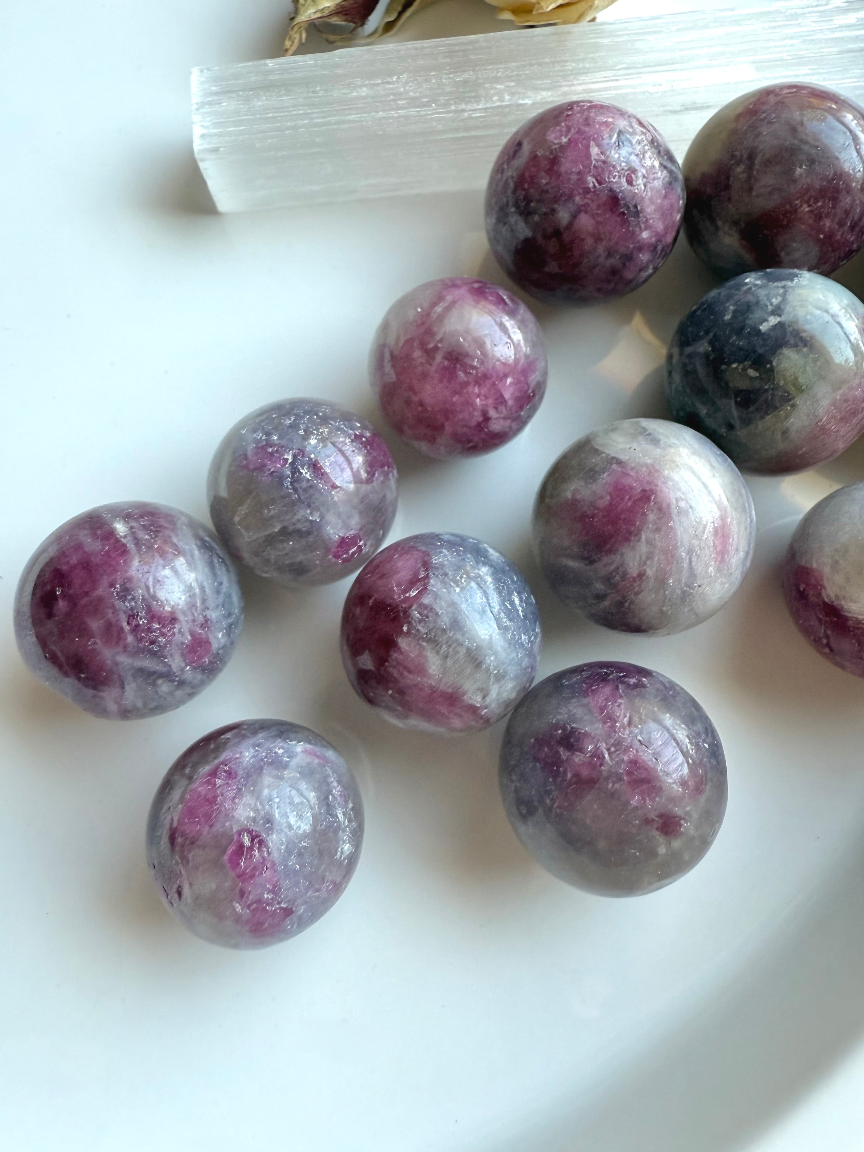Closeup of polished Unicorn Stone mini spheres highlighting pink tourmaline and lepidolite matrix