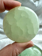 Close-up of a seafoam green Pistachio Calcite meditation stone showing natural crystalline texture and calming glow