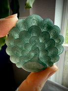 Blue Water Jade peacock medallion held to the light showing lovely translucence and rich blue-green color