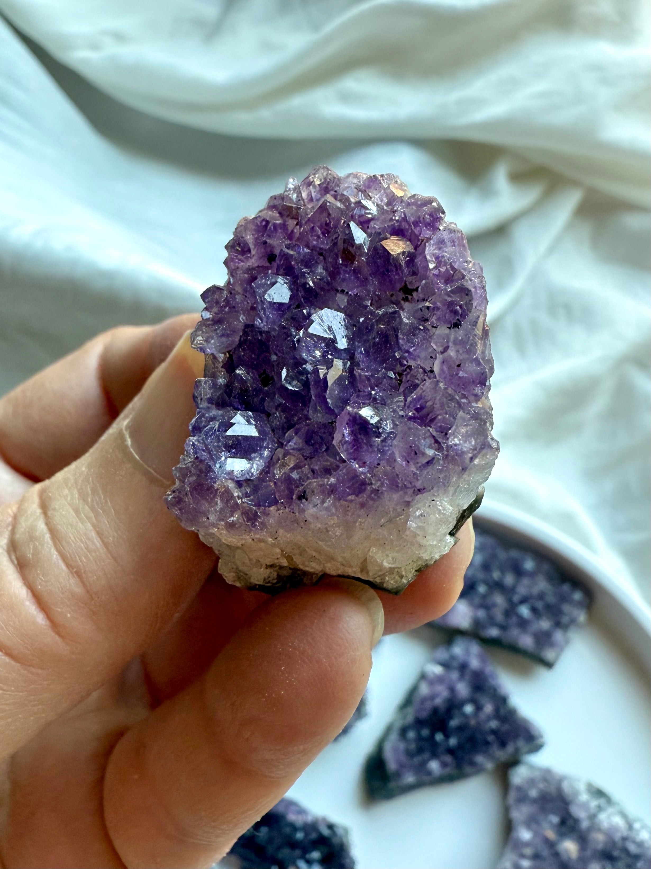 Amethyst cluster with sparkling purple points held in hand + natural chalcedony geode matrix edges