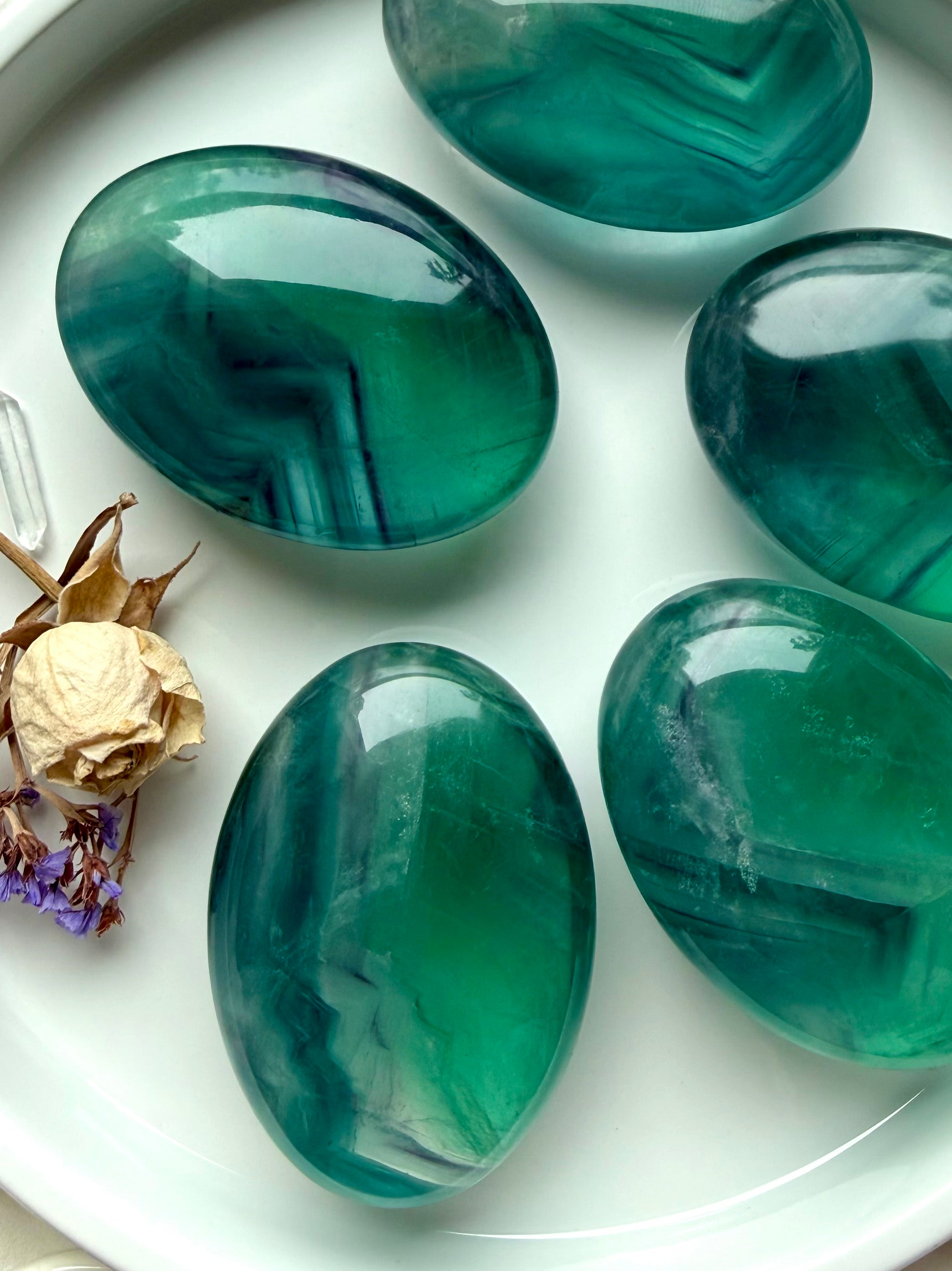 Group of large teal fluorite palm stones displaying saturated blue green banding and natural internal movement