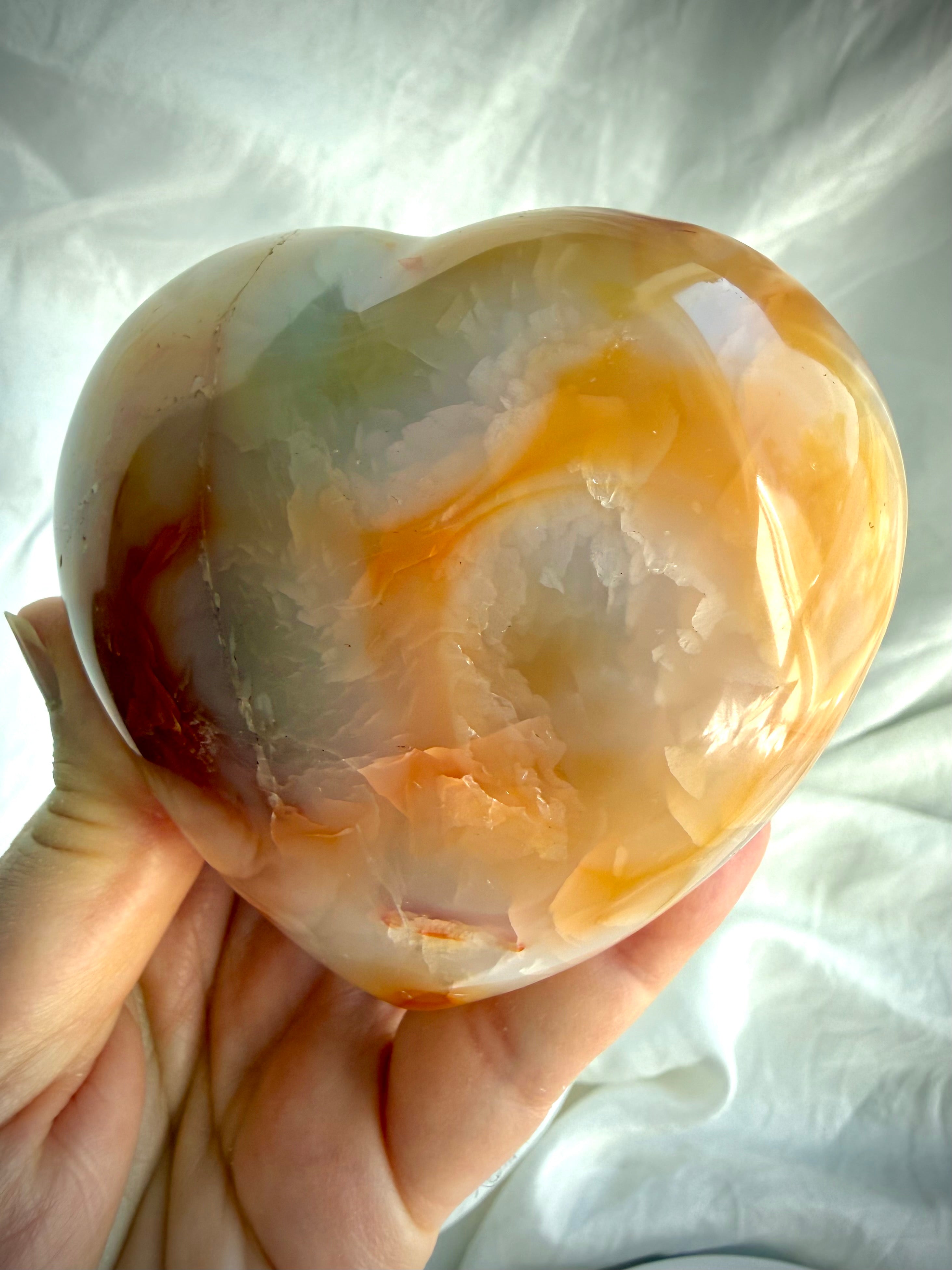 Large polished Carnelian heart with soft orange and cream swirls in natural light, one-of-a-kind healing crystal