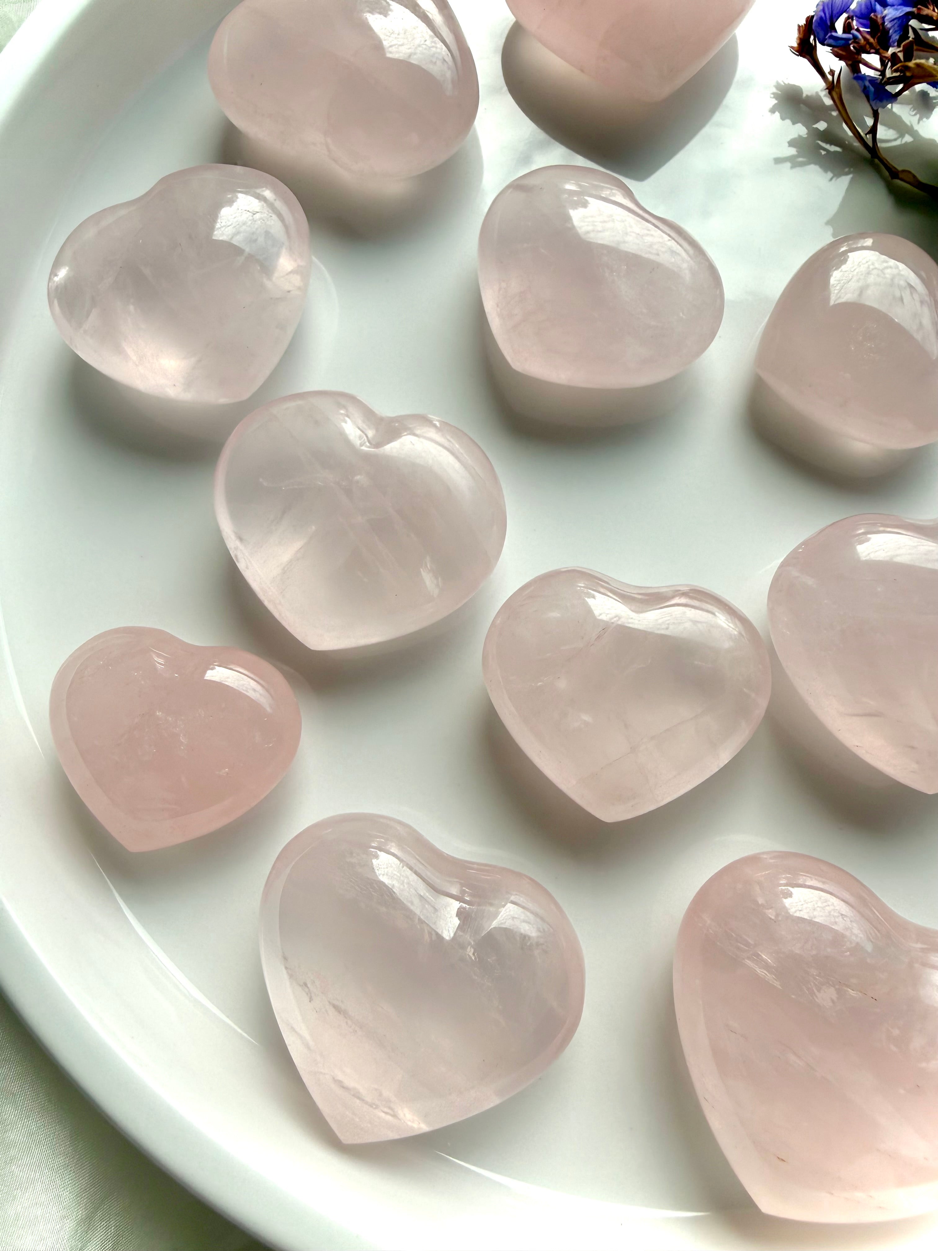 Close up of rose quartz hearts with smooth polish and natural inclusions, pink crystal hearts for emotional healing