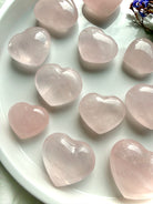 Close up of rose quartz hearts with smooth polish and natural inclusions, pink crystal hearts for emotional healing