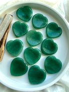 green aventurine heart worry stones displayed on white tray, polished crystal hearts for luck, abundance and emotional healing