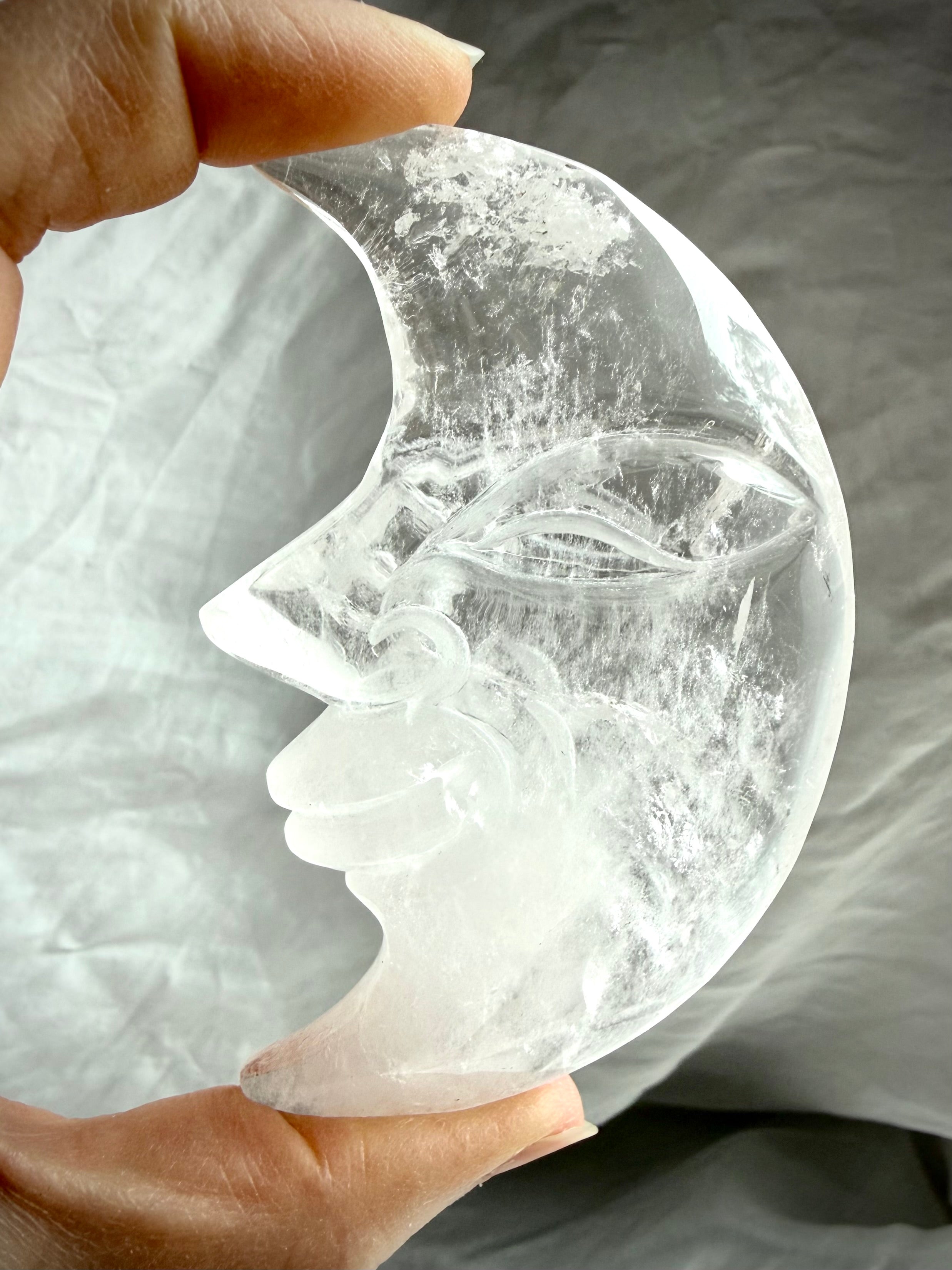 Close-up of Clear Quartz Moon Face carving highlighting detailed facial features and luminous transparent crystal