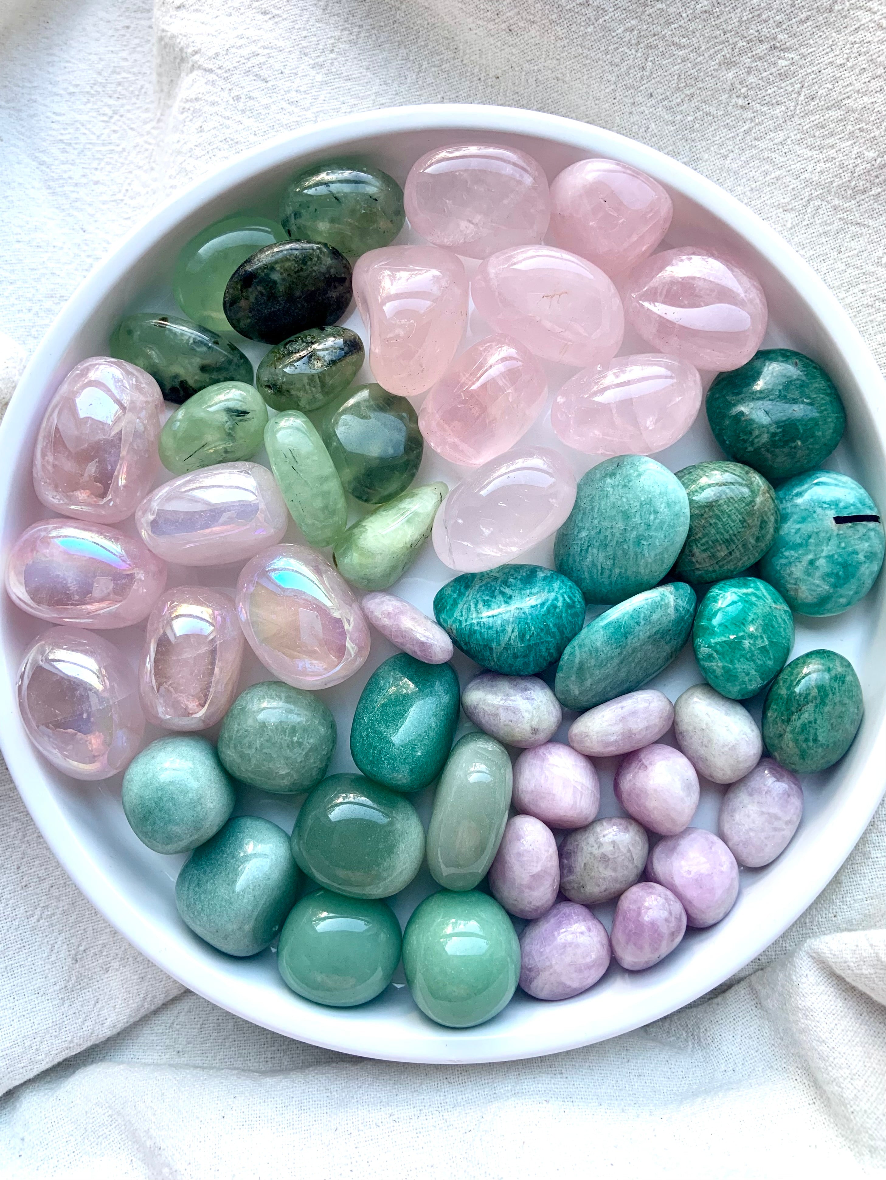 Overhead image of Heart Chakra stones arranged on a white plate — a full set of pink and green crystals for chakra alignment and heart-centered energy healing.