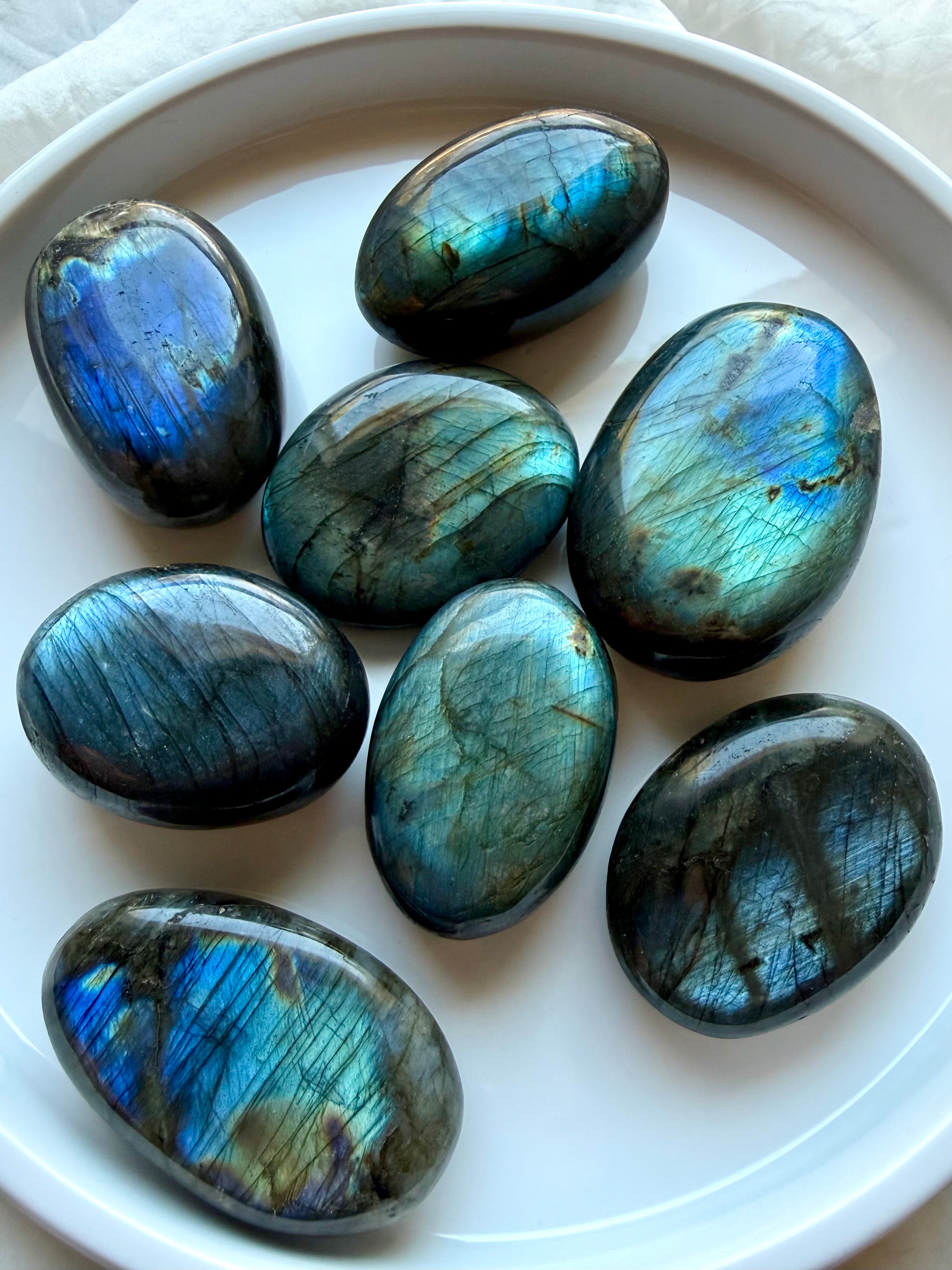 Assorted Labradorite palm stones with blue, teal and green flash in polished oval shapes