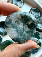 Moss Agate heart worry stone held in hand with rich moss inclusions and natural translucent quartz