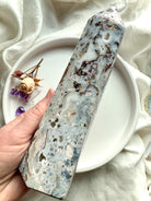 Large Cosmic Ocean Jasper tower held in hand, featuring layered chalcedony, organic earth tones, and subtle druzy sparkle