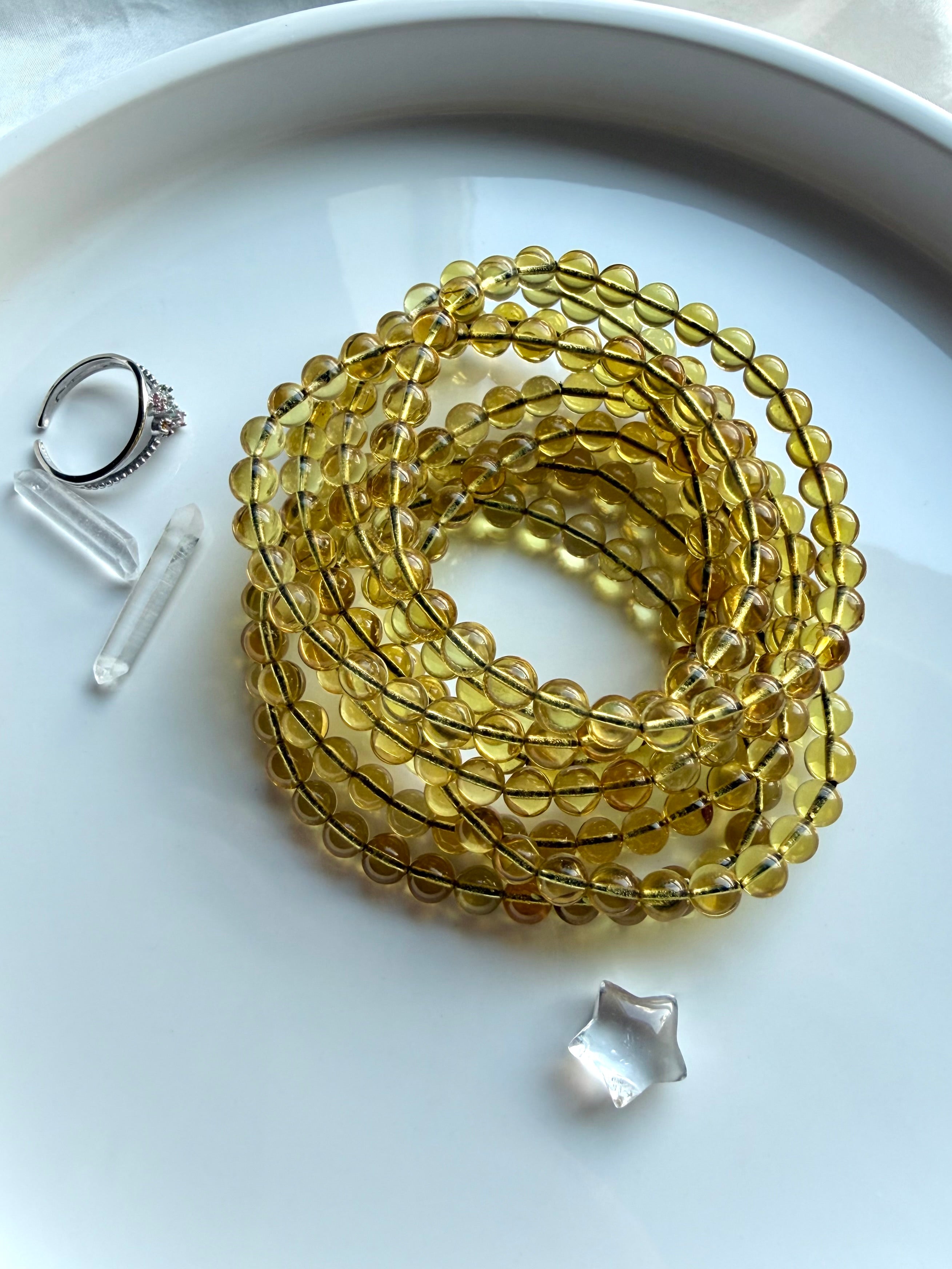 Indonesian blue amber bead bracelets coiled on dish – UV reactive amber crystal jewelry