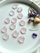 Angled view of wide plate of rose quartz hexagon crystals with roses, clear quartz point and amethyst heart, sacred geometry carvings for grids or décor