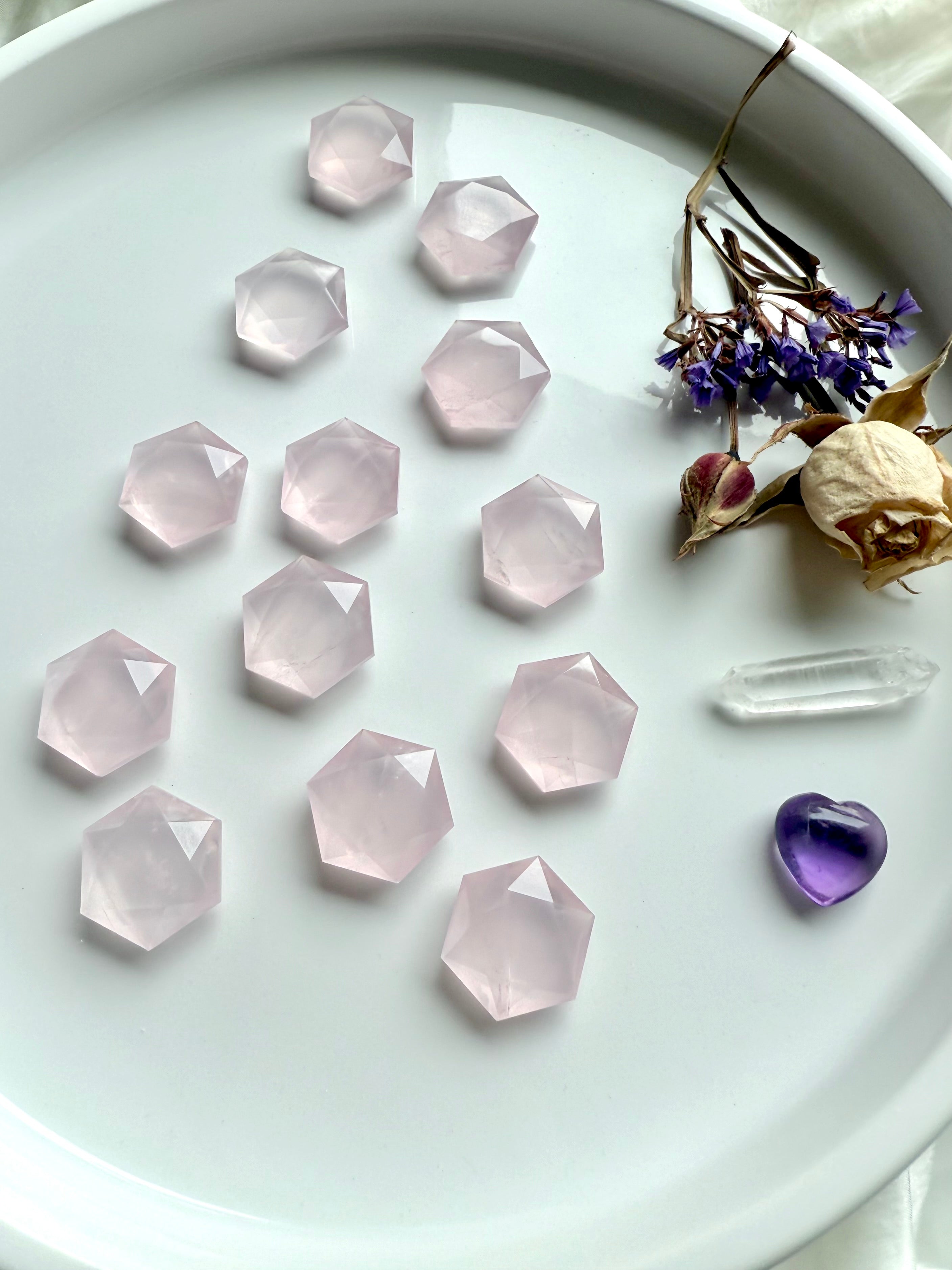 Angled view of wide plate of rose quartz hexagon crystals with roses, clear quartz point and amethyst heart, sacred geometry carvings for grids or décor