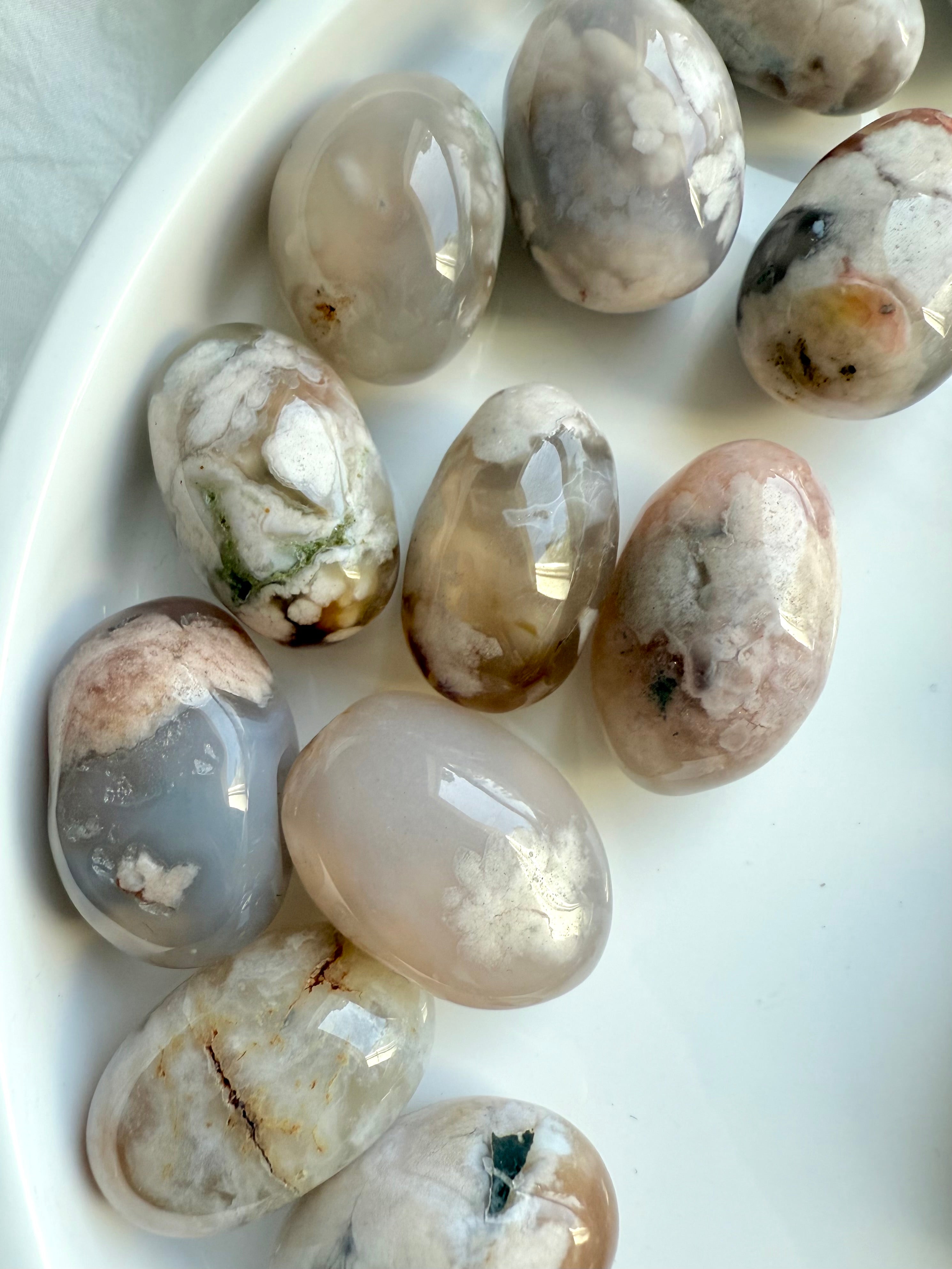 Close up of high quality Flower Agate tumbled stones with beautiful pastel colors on a white plate