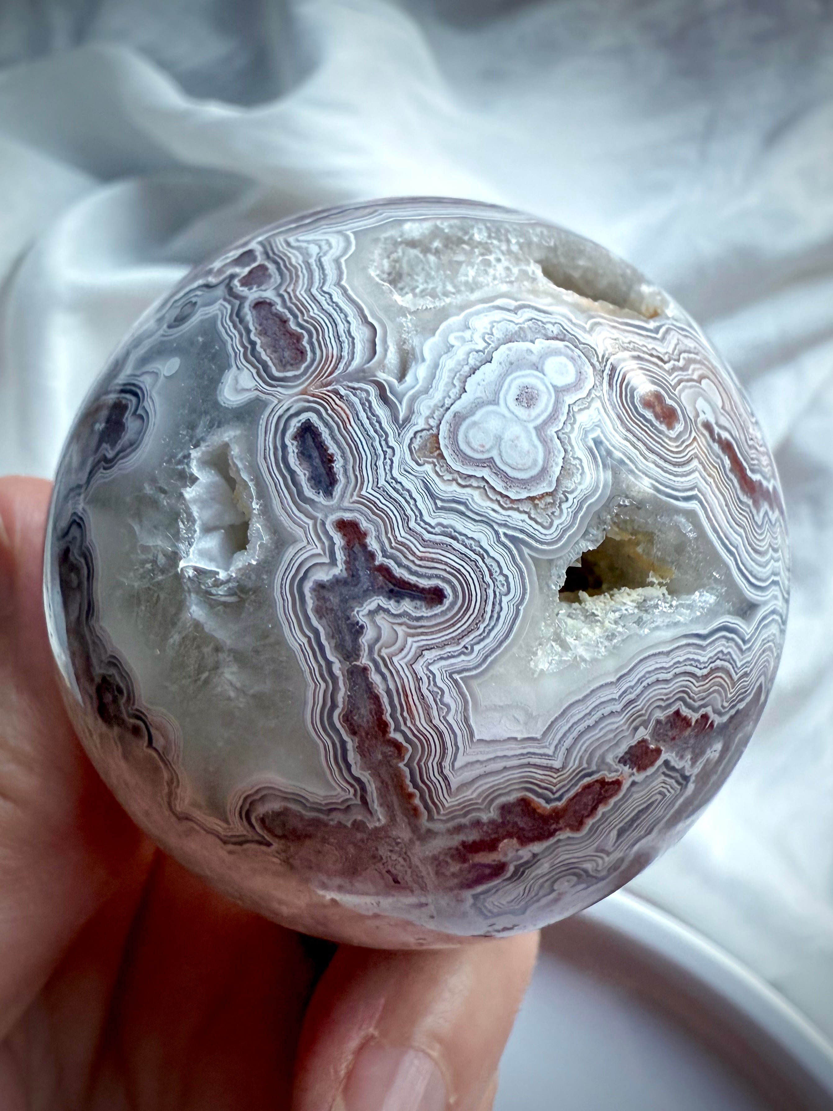 Joyful Crazy Lace Agate sphere showing deep red lace patterns, open geode cavity, and intricate natural banding