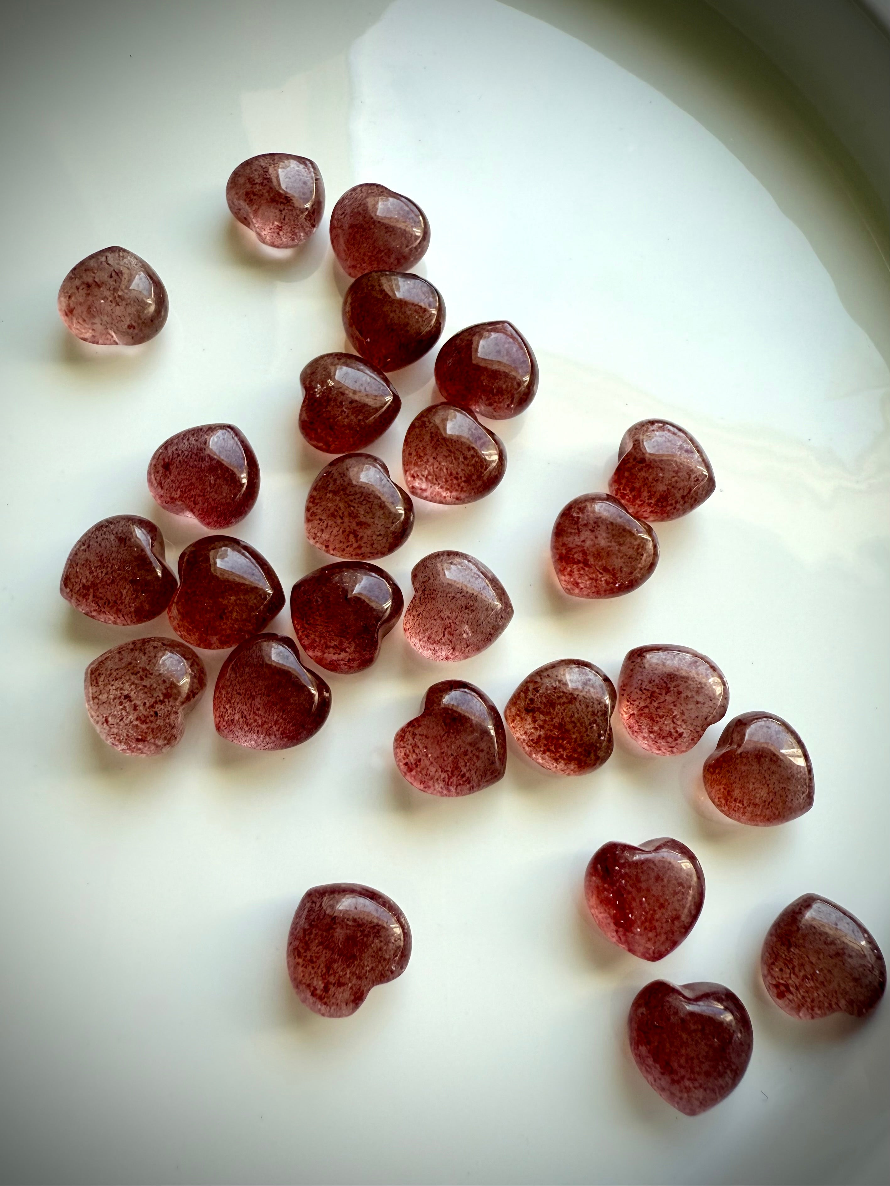 Angled array of Strawberry Quartz mini hearts on a white plate — tanzberry quartz crystals for heart chakra healing, love, and emotional balance.