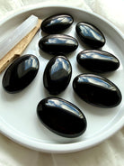 Black Obsidian palm stones with glossy mirror-like finish for grounding, protection, meditation, and Root Chakra healing