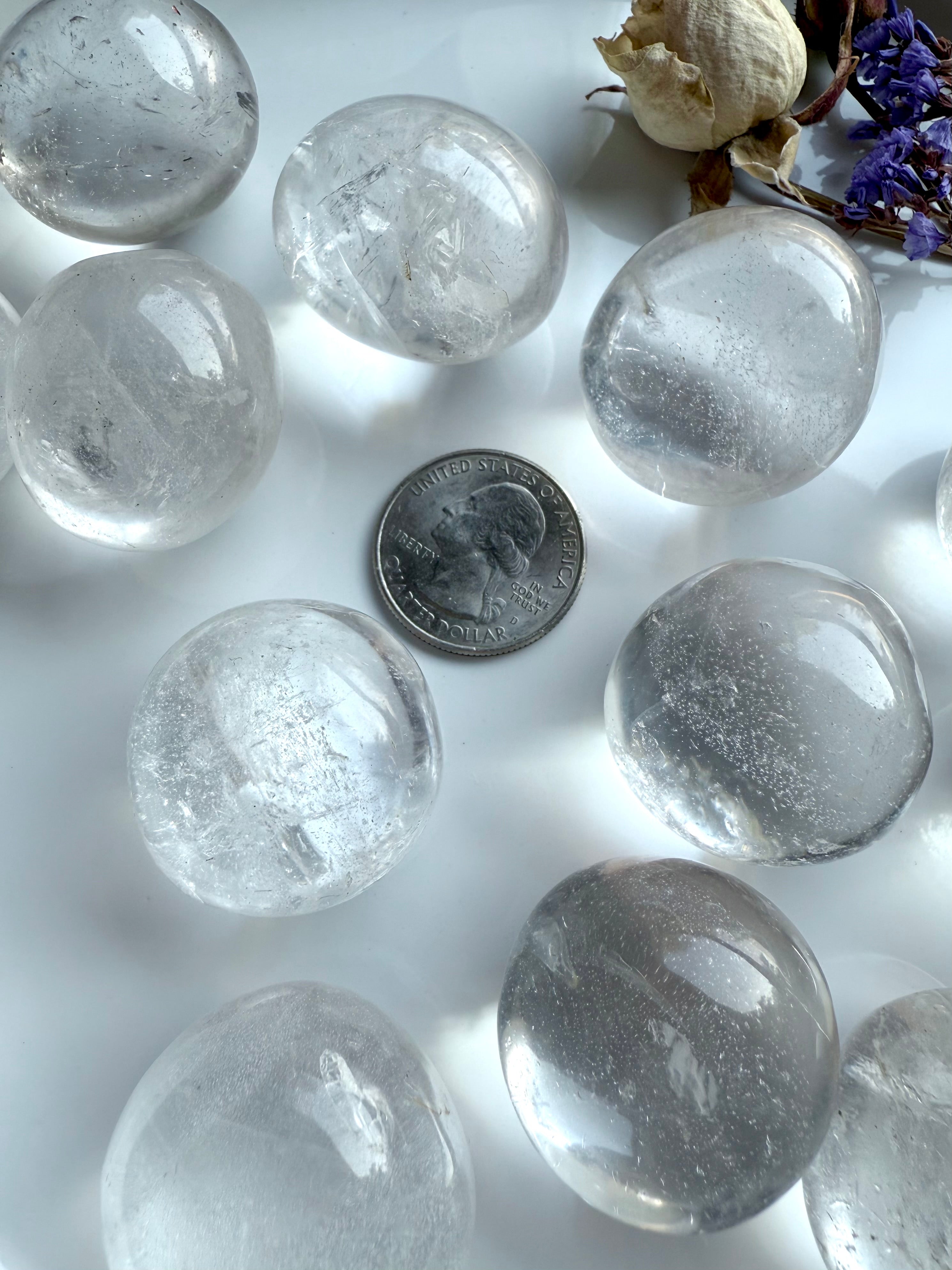 Array of Clear Quartz tumbled stones with US quarter coin for scale reference