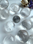 Array of Clear Quartz tumbled stones with US quarter coin for scale reference