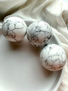 Three Howlite crystal spheres arranged in white tray, polished white stone with natural gray spiderweb veining for calm, sleep and anxiety relief