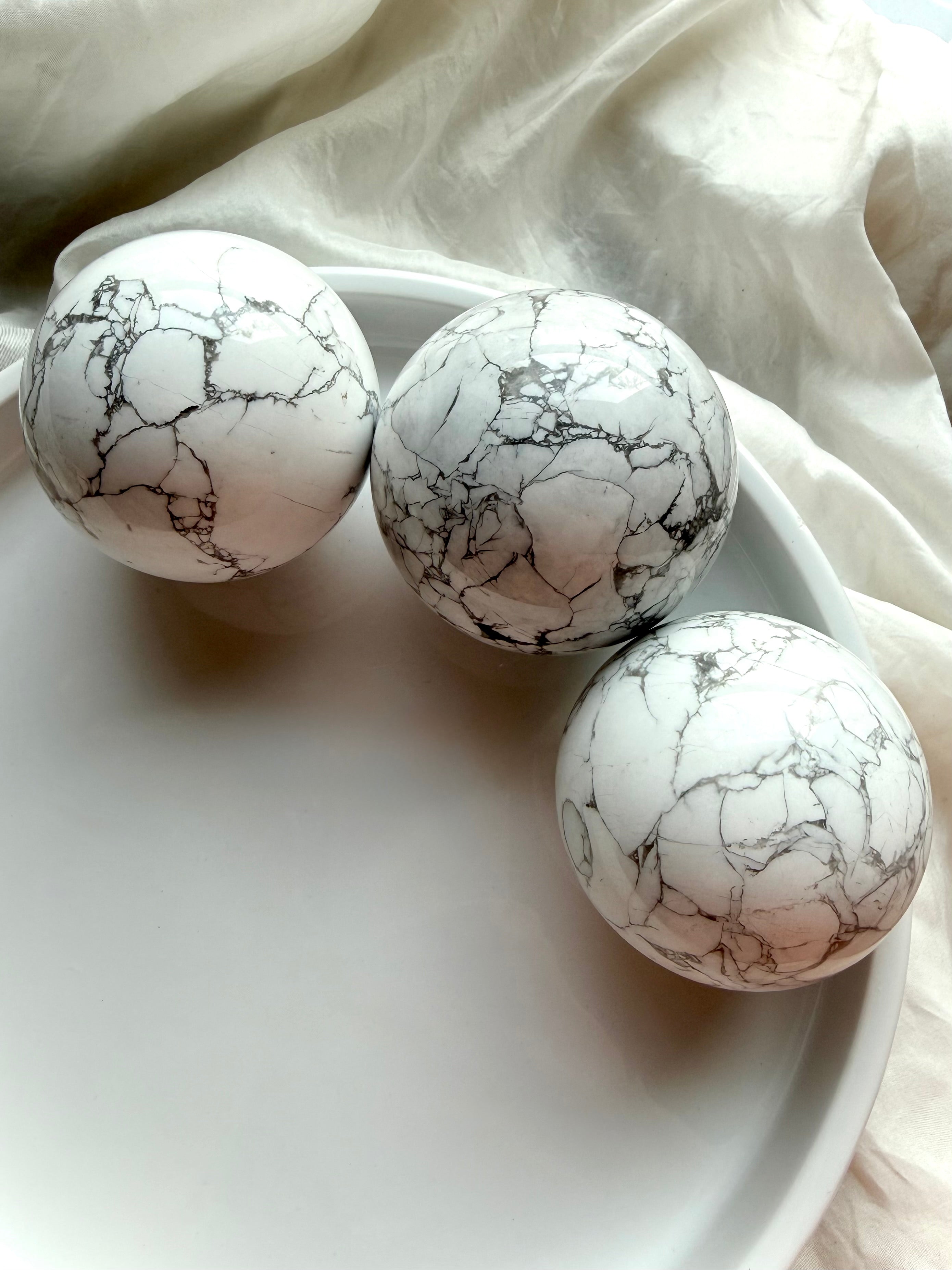 Three Howlite crystal spheres arranged in white tray, polished white stone with natural gray spiderweb veining for calm, sleep and anxiety relief