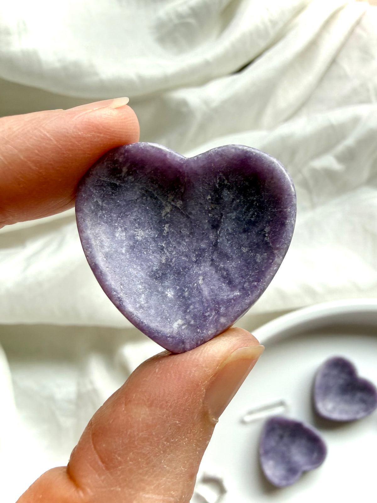 Mini Lepidolite heart bowl held between fingers showing petite size, purple color and shallow jewelry dish shape