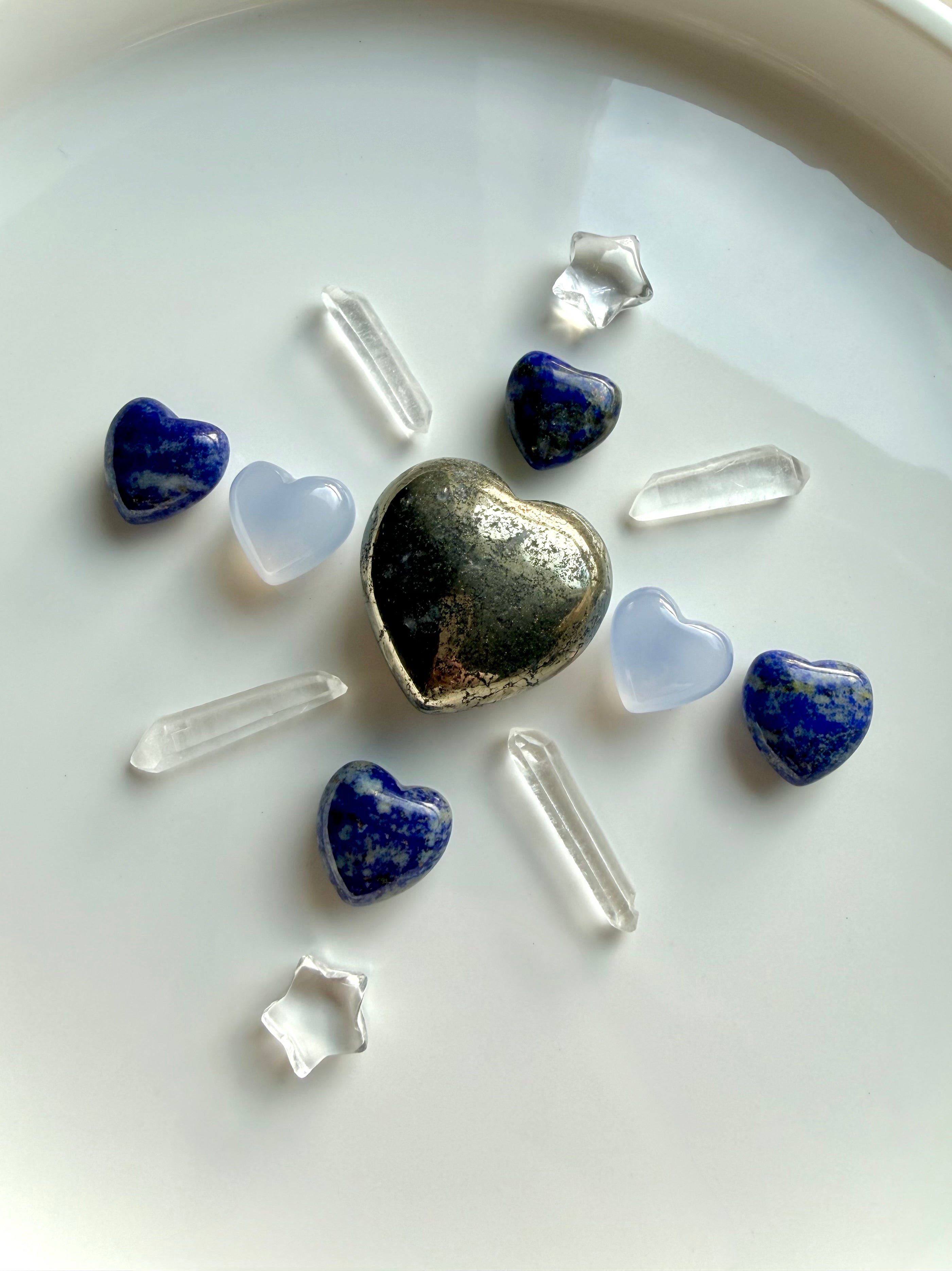 Crystal grid featuring pyrite heart centerpiece with blue chalcedony hearts, lapis lazuli hearts, clear quartz points, and star carvings for clarity, communication, and heart-centered intention