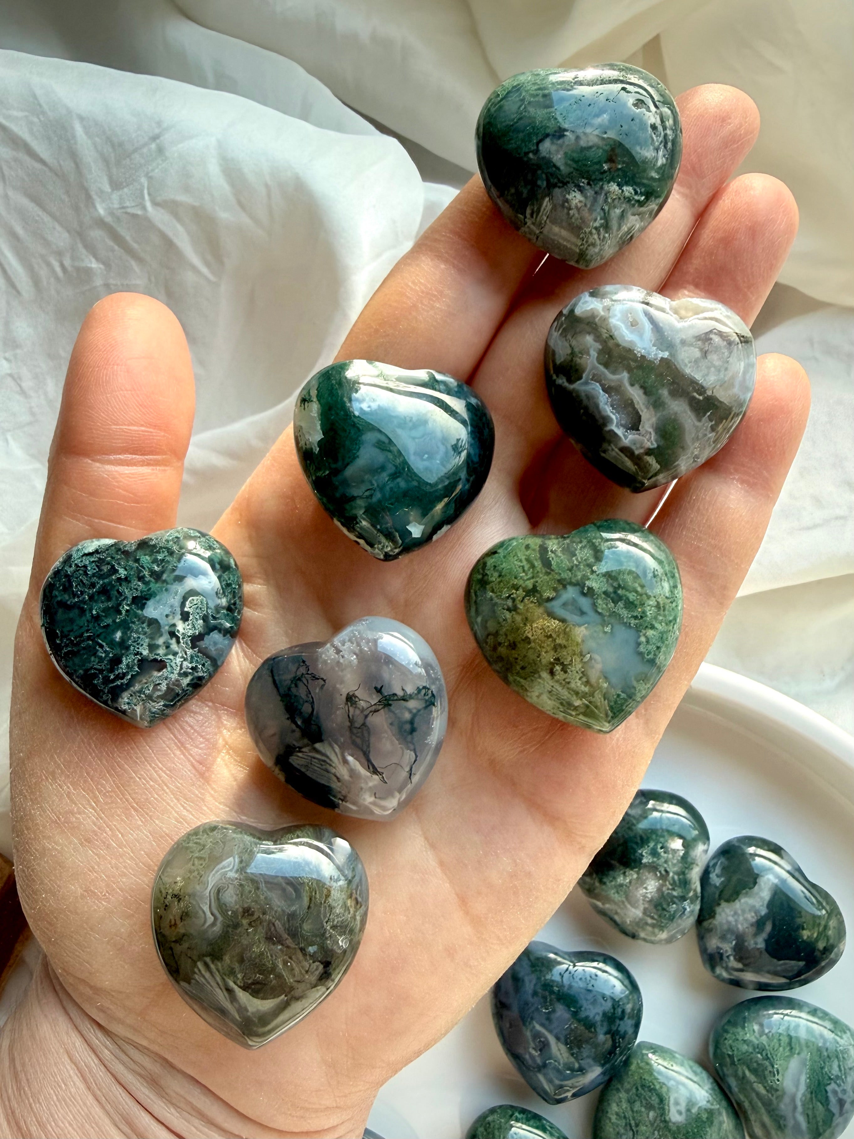 Moss Agate crystal hearts held in hand, showing size, polish, and natural moss inclusions
