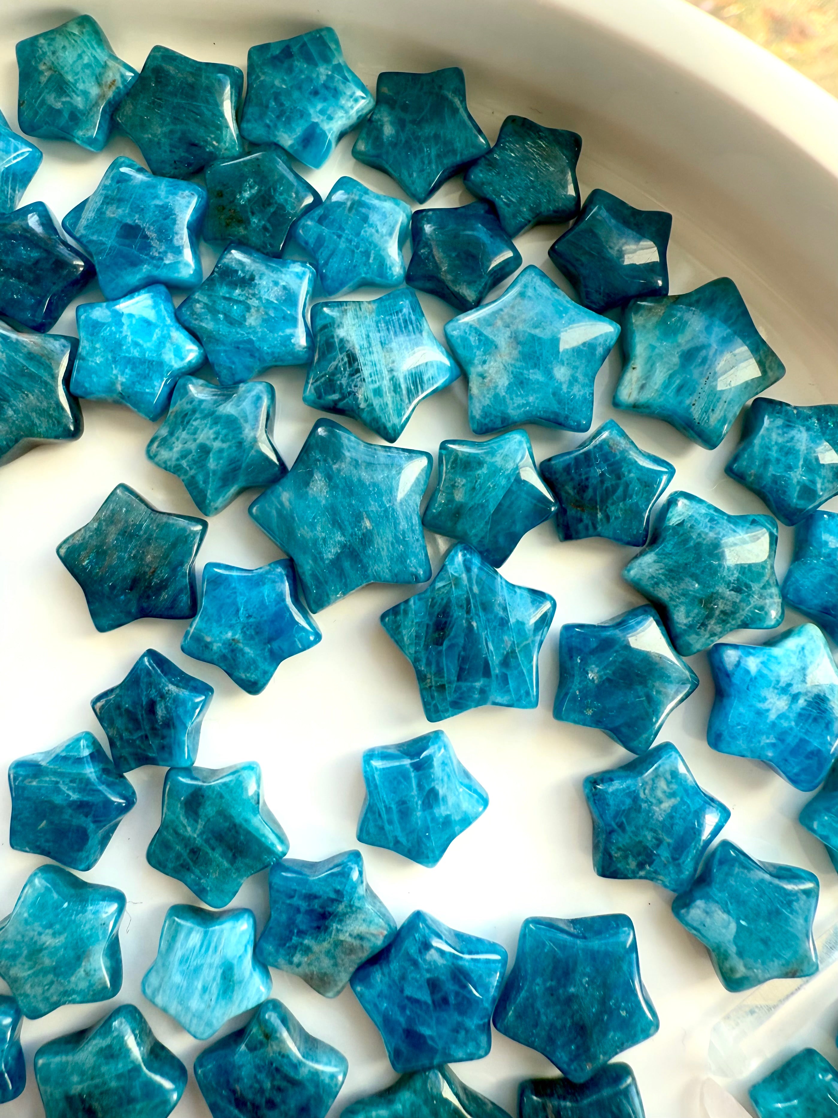 Wide angle view of Blue Apatite stars on a white plate — mini carved crystal stars for clarity, communication & Throat Chakra energy work.