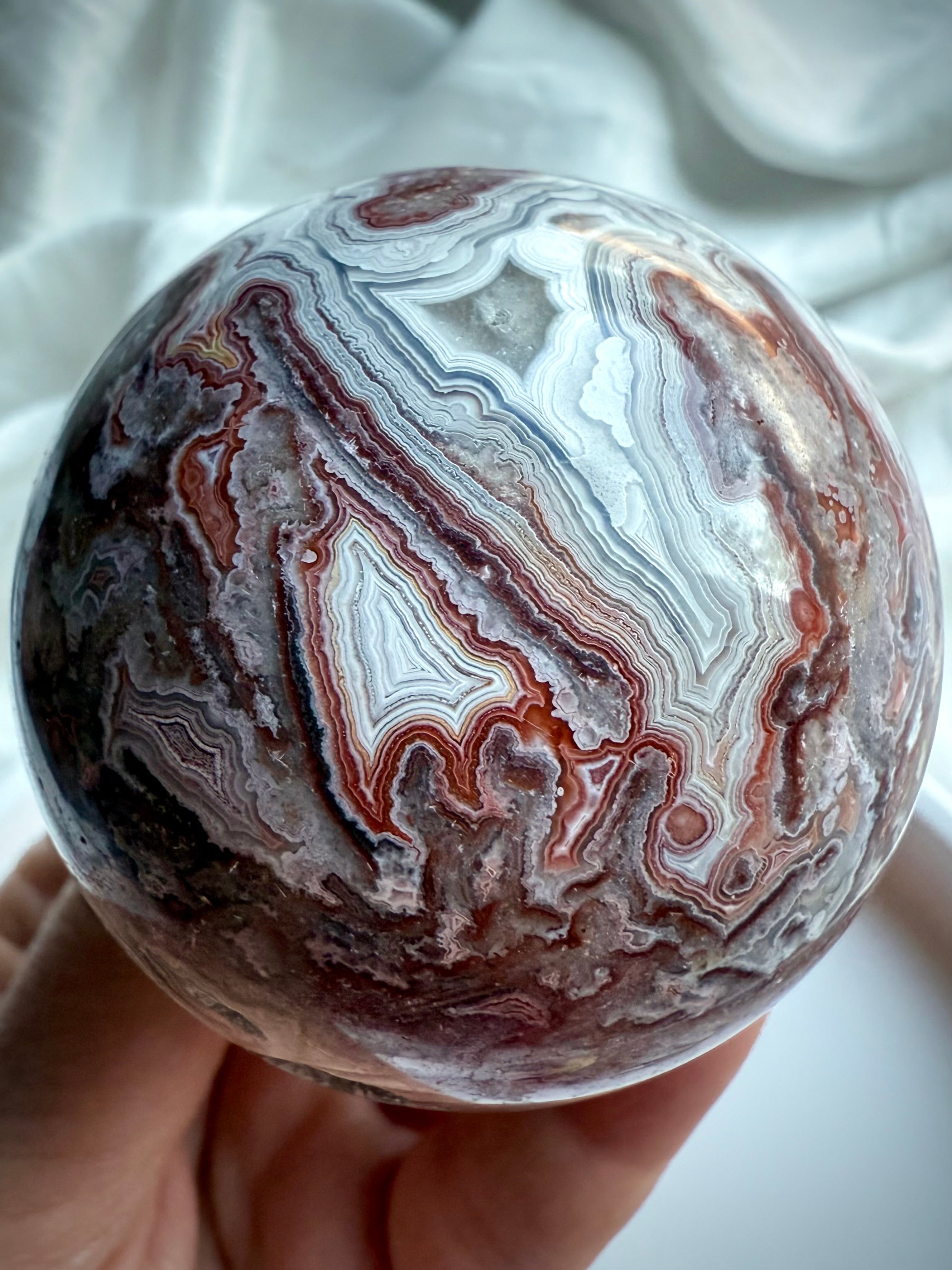 Crystal sphere showcasing lace-like Crazy Lace Agate patterns with deep grounding colors and earthy textures