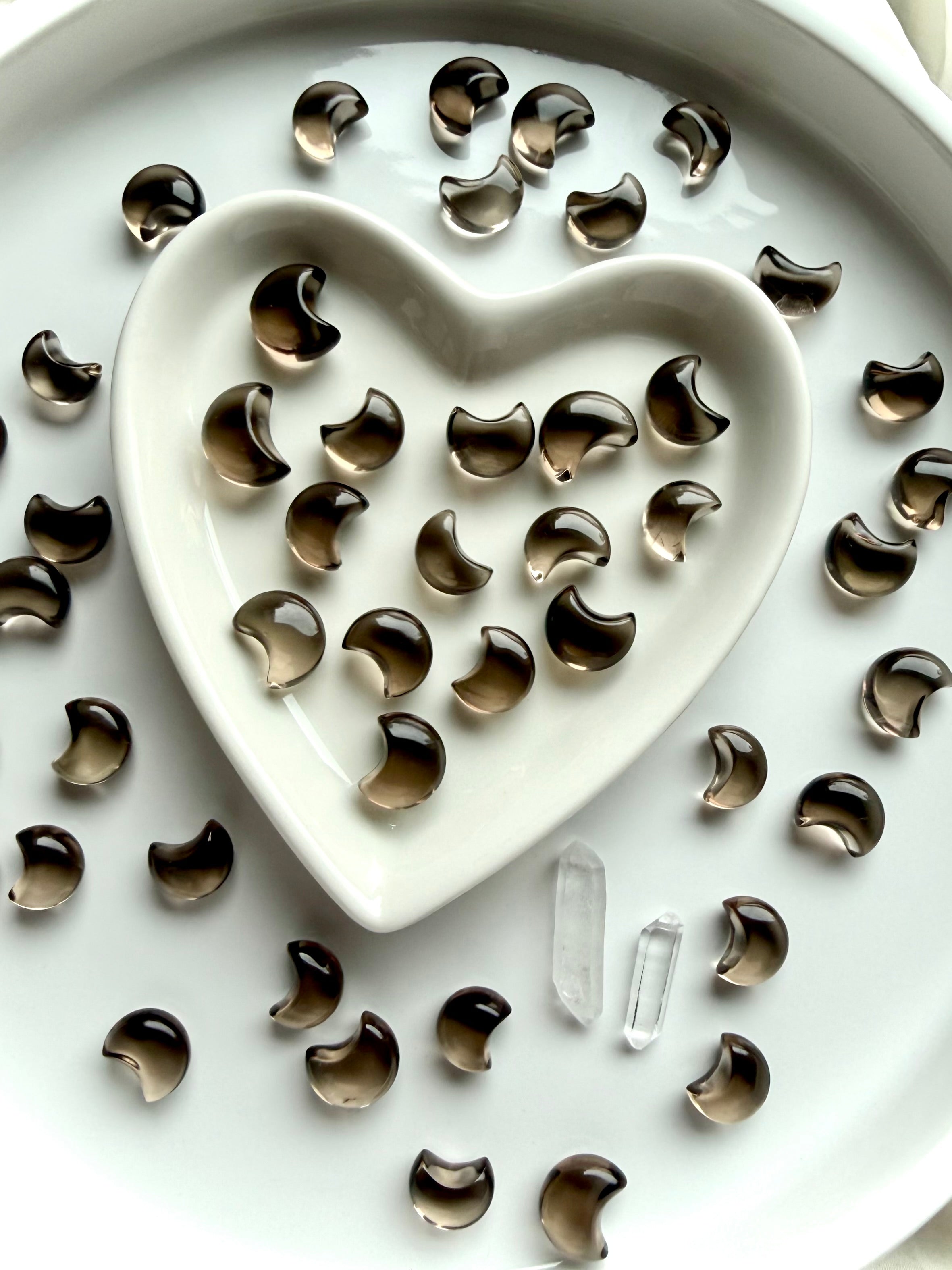 Mini Smoky Quartz moons arranged around a heart-shaped crystal dish with tiny crescent carvings and celestial crystals