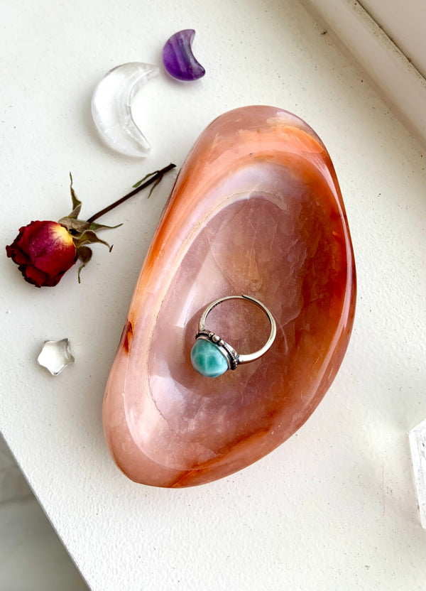 A beautiful orange Carnelian Offering Bowl or Ring Dish with a natural oval shape shown from above with a ring inside for scale. A natural crystal bowl makes a unique and special gift for any crystal lover.