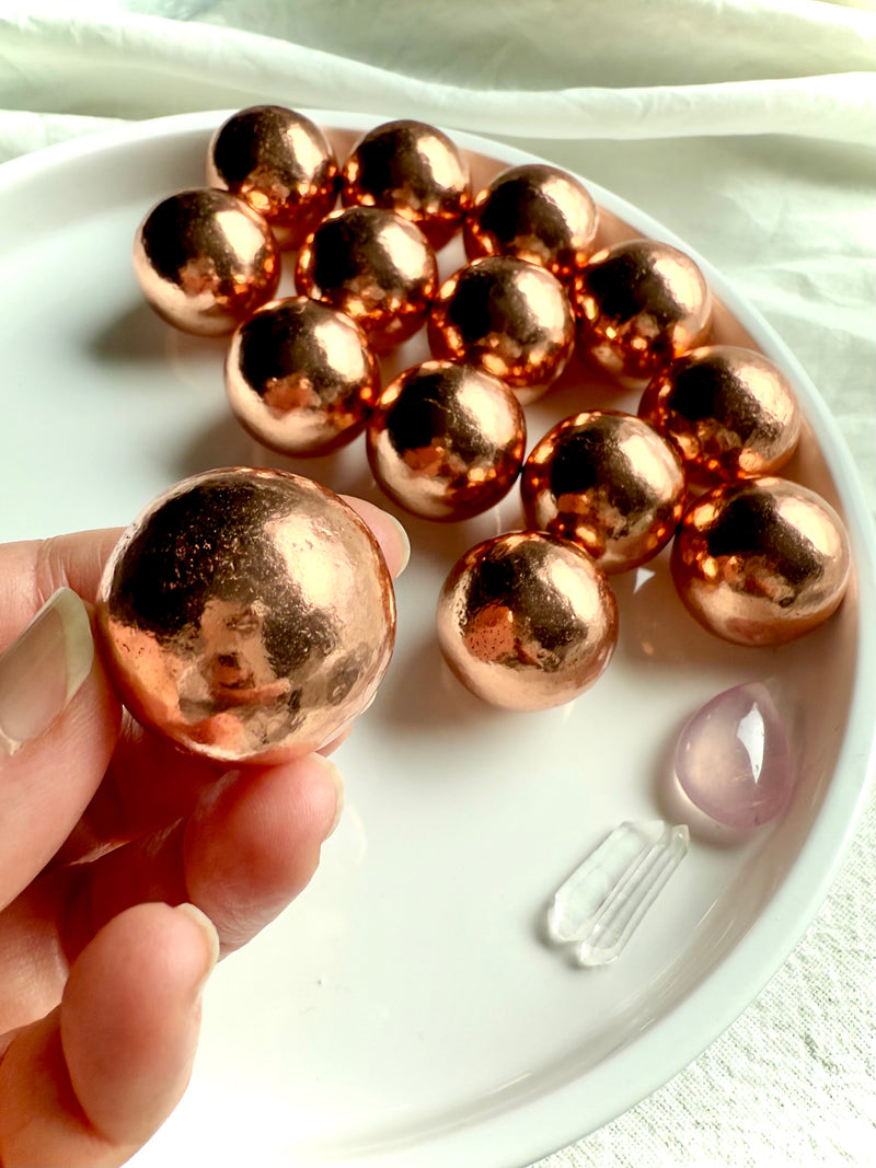 Michigan copper spheres shown in my fingertips for scale with a plate of mini copper balls