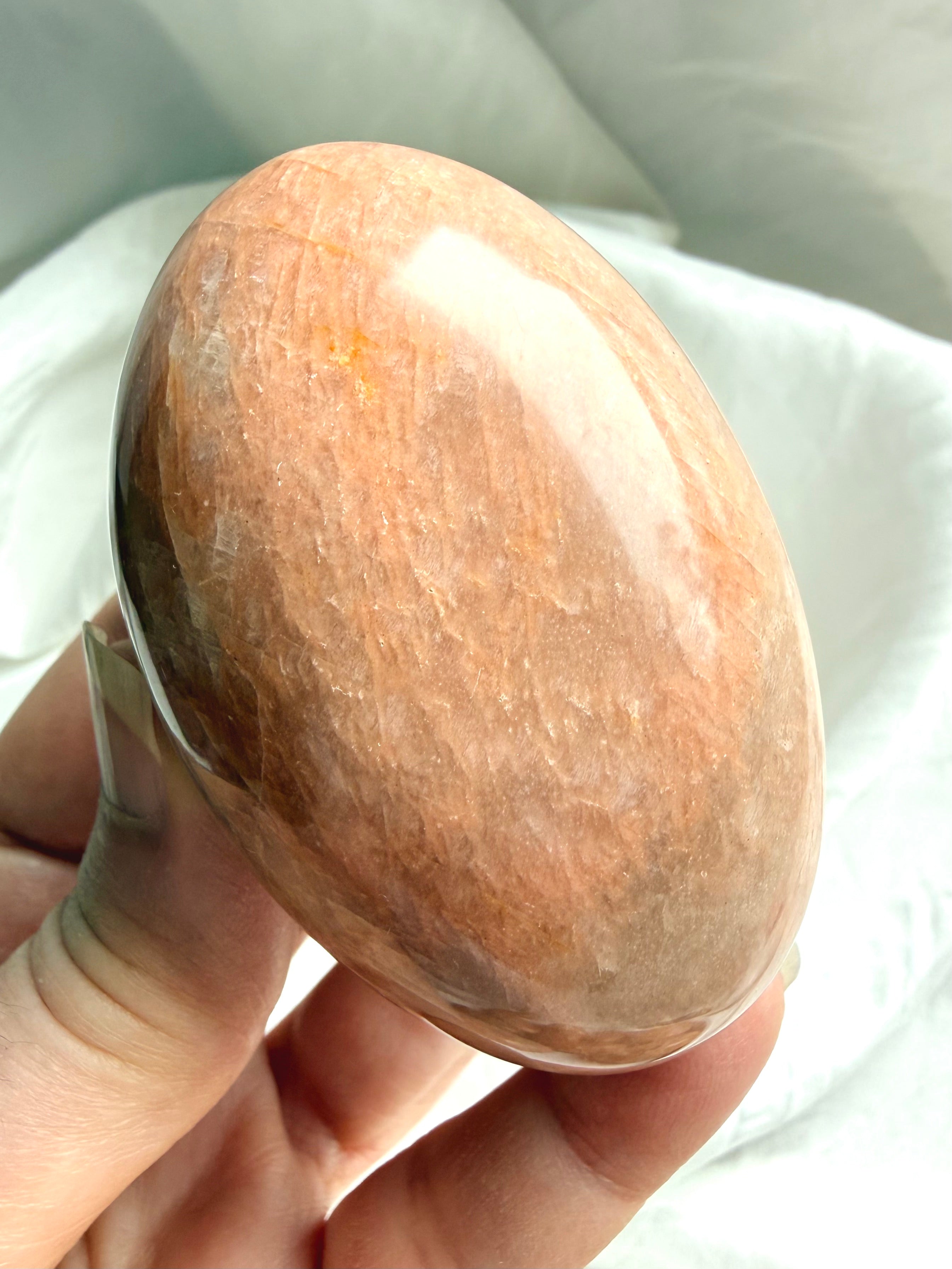 Smooth polished Peach Moonstone palm stone with soft peach and beige natural banding